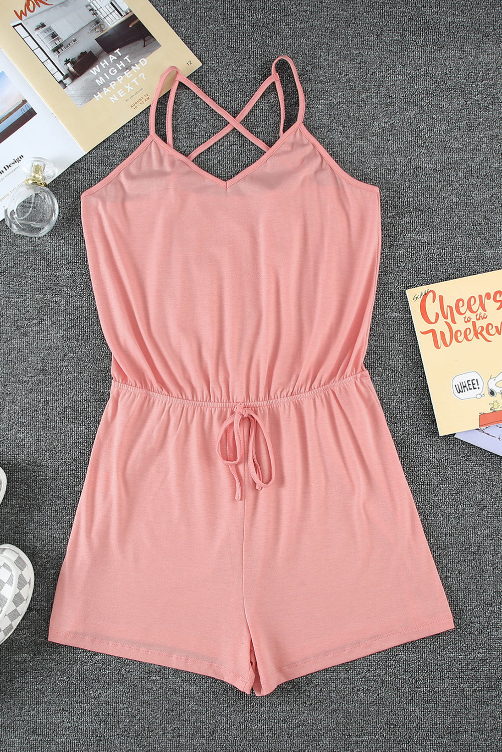 A stylish pink romper featuring spaghetti straps, a V-neckline, and a crisscross back design, perfect for a night out.