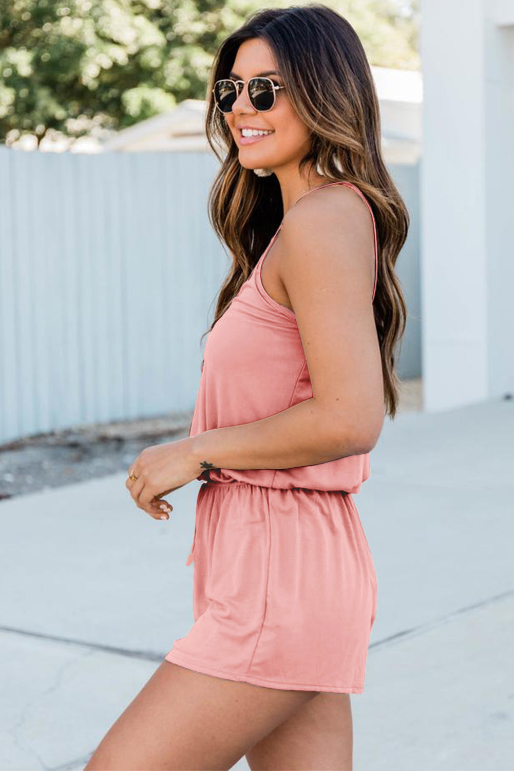 A stylish pink romper featuring spaghetti straps, a V-neckline, and a crisscross back design, perfect for a night out.