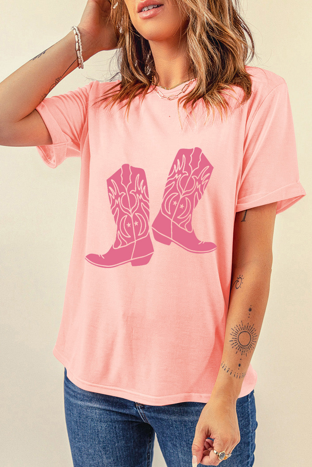 A stylish pink t-shirt featuring a cowboy boots print, perfect for casual wear, with a round neck and short sleeves.