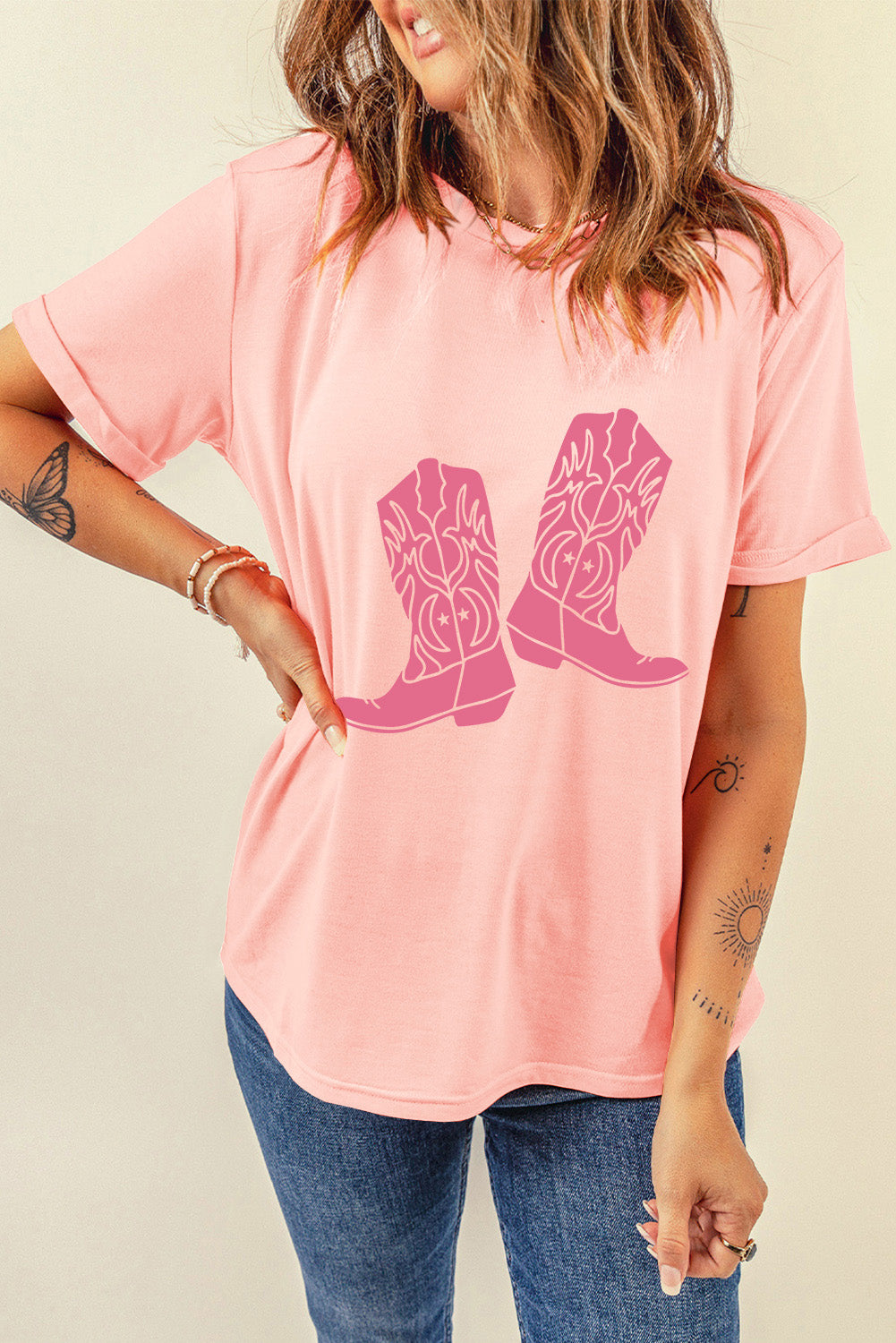 A stylish pink t-shirt featuring a cowboy boots print, perfect for casual wear, with a round neck and short sleeves.