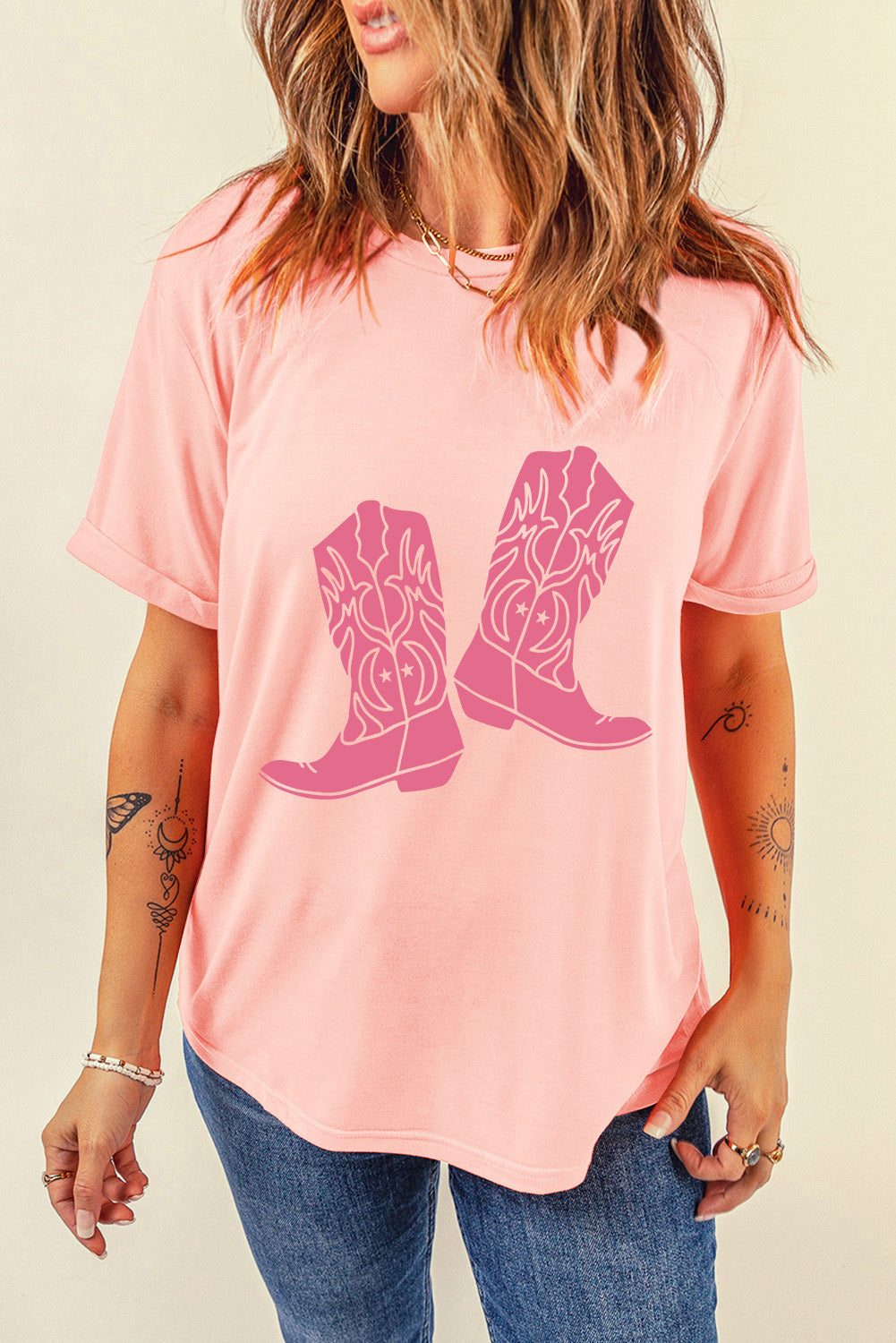 A stylish pink t-shirt featuring a cowboy boots print, perfect for casual wear, with a round neck and short sleeves.