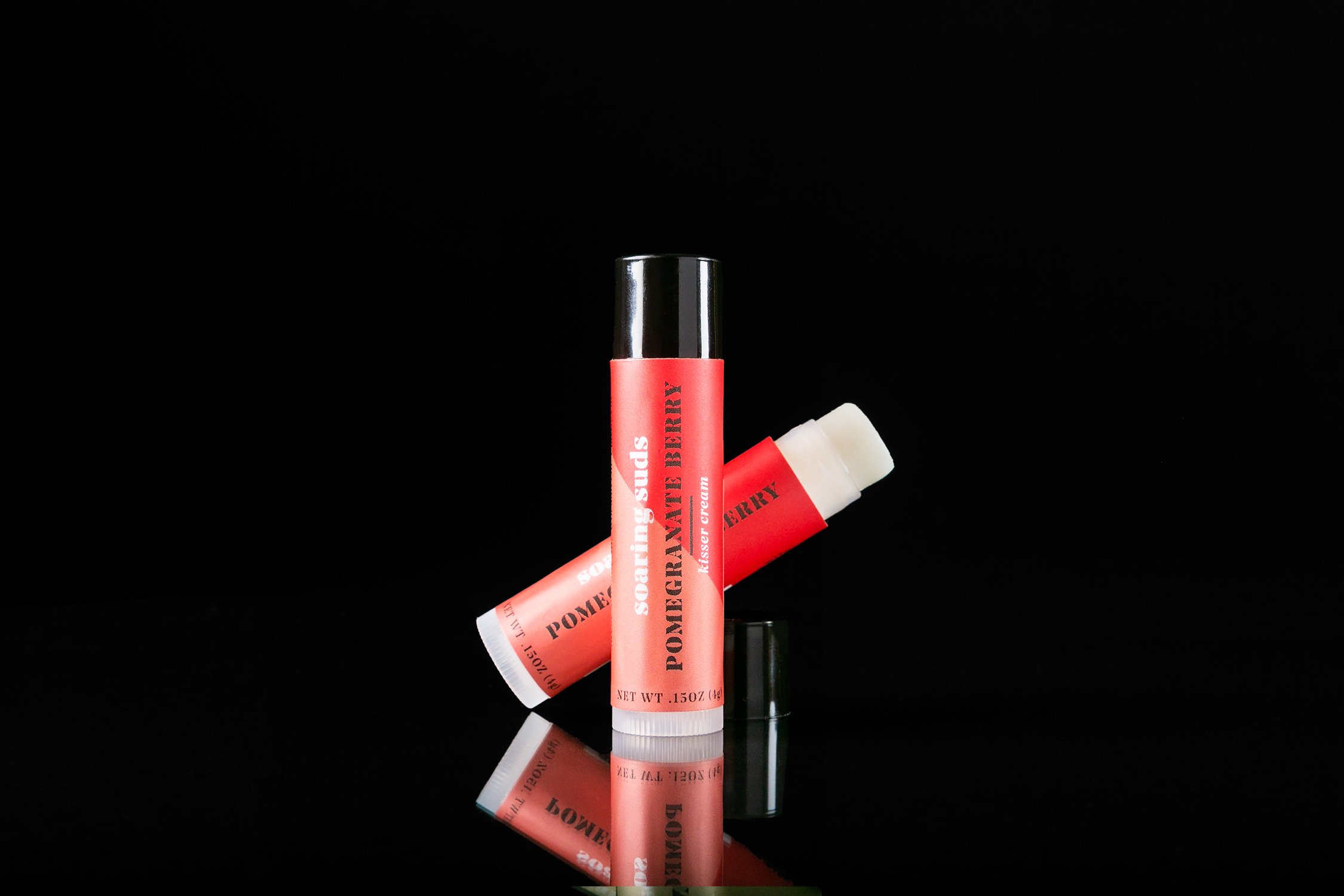 Pomegranate Berry Kisser Cream lip balm tube with a fruity pomegranate design, showcasing its natural ingredients.