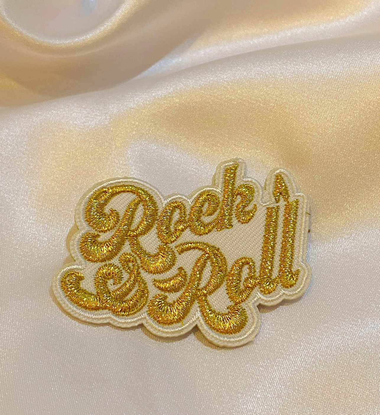 A vibrant 'Rock & Roll' iron-on patch featuring metallic gold thread on a black background, measuring 2.5 inches.