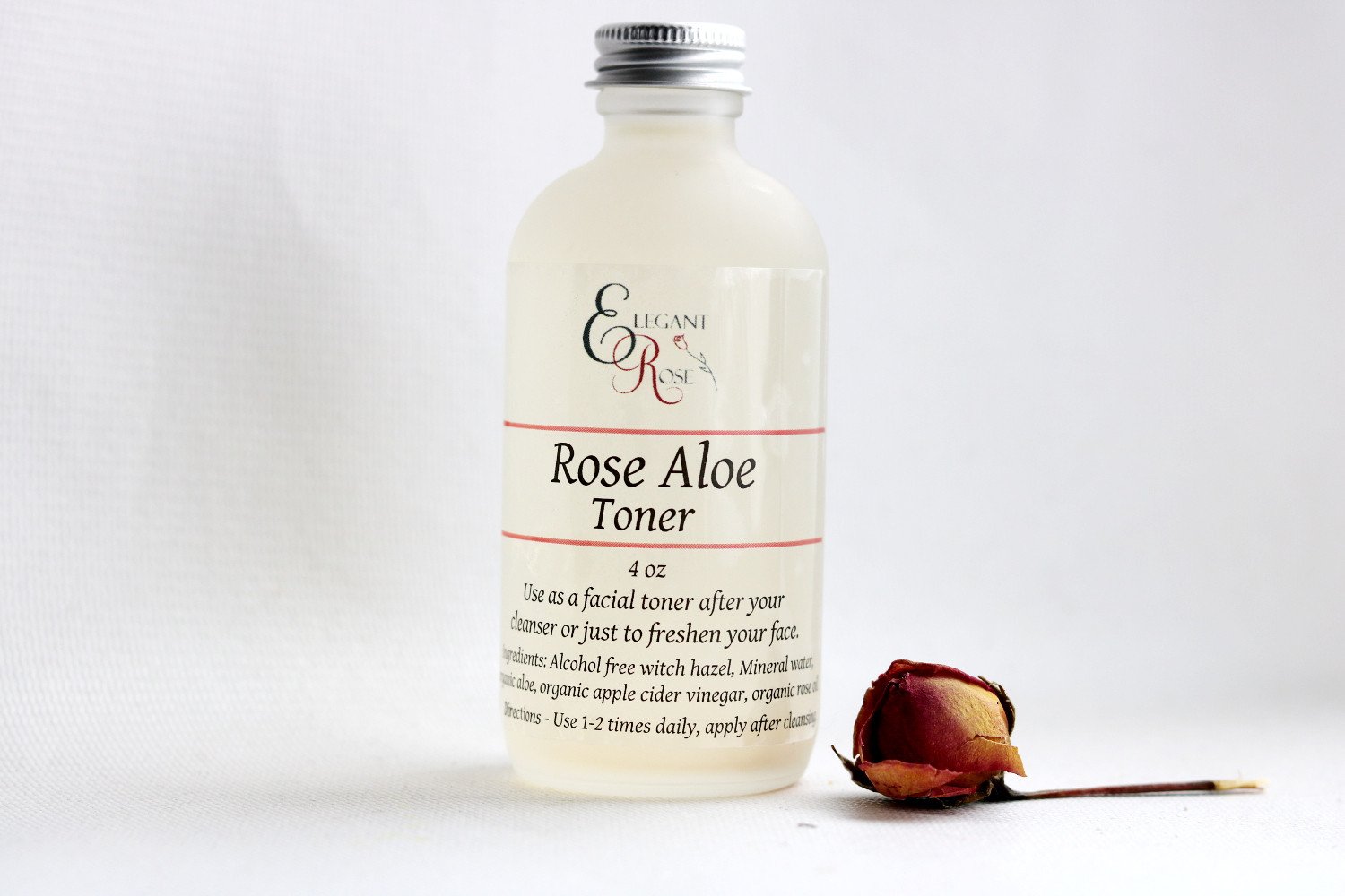 A 4-ounce bottle of Rose Aloe Facial Toner, featuring a blend of natural ingredients for dry and normal skin types, with a soft pink hue and elegant label.