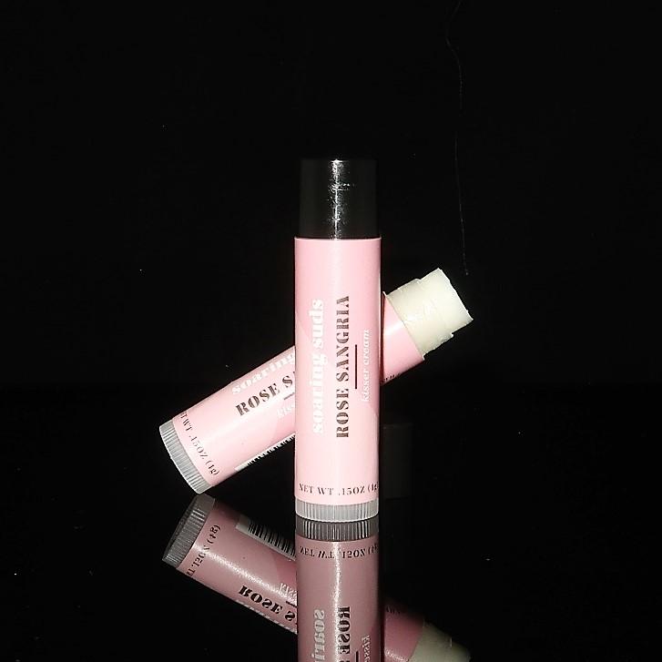 A tube of Rose Sangria Kisser Cream lip balm with a floral design, showcasing its natural ingredients and refreshing scent.