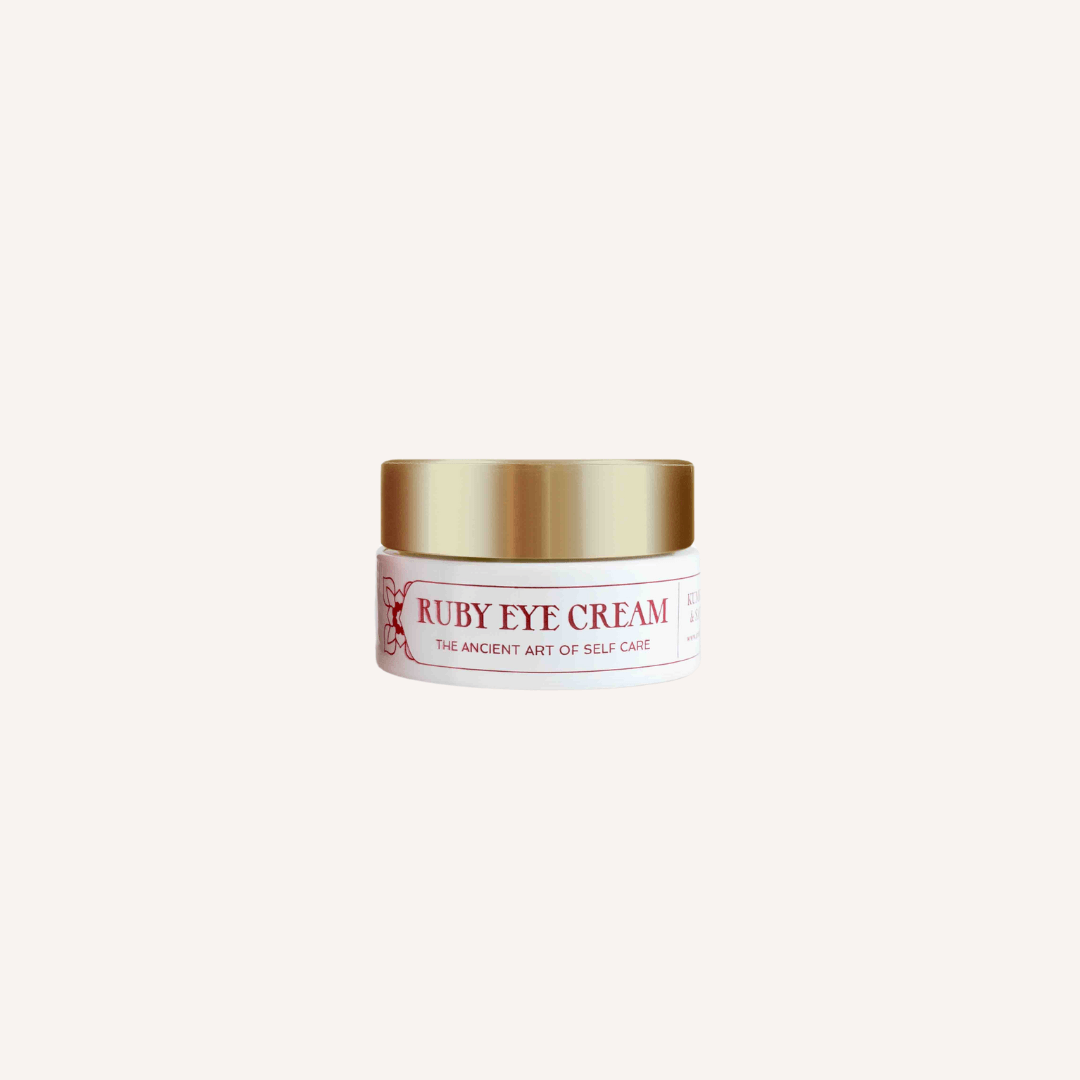 A jar of Ruby Eye Cream featuring a rich, creamy texture, surrounded by Ayurvedic herbs and saffron strands.