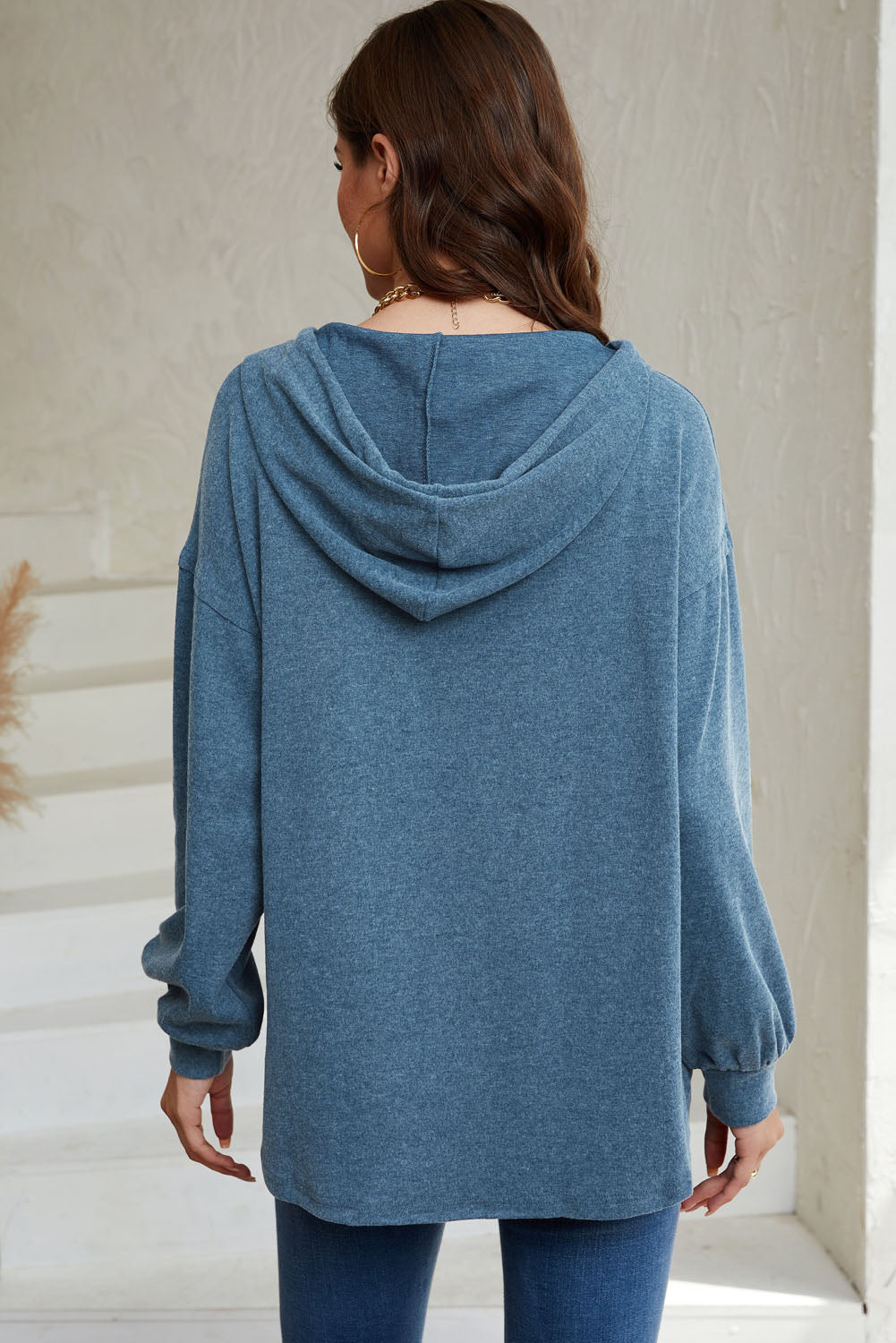 Sky Blue Buttoned High and Low Hem Hoodie with drawstring hood and tortoiseshell buttons, showcasing a relaxed fit and side slits.