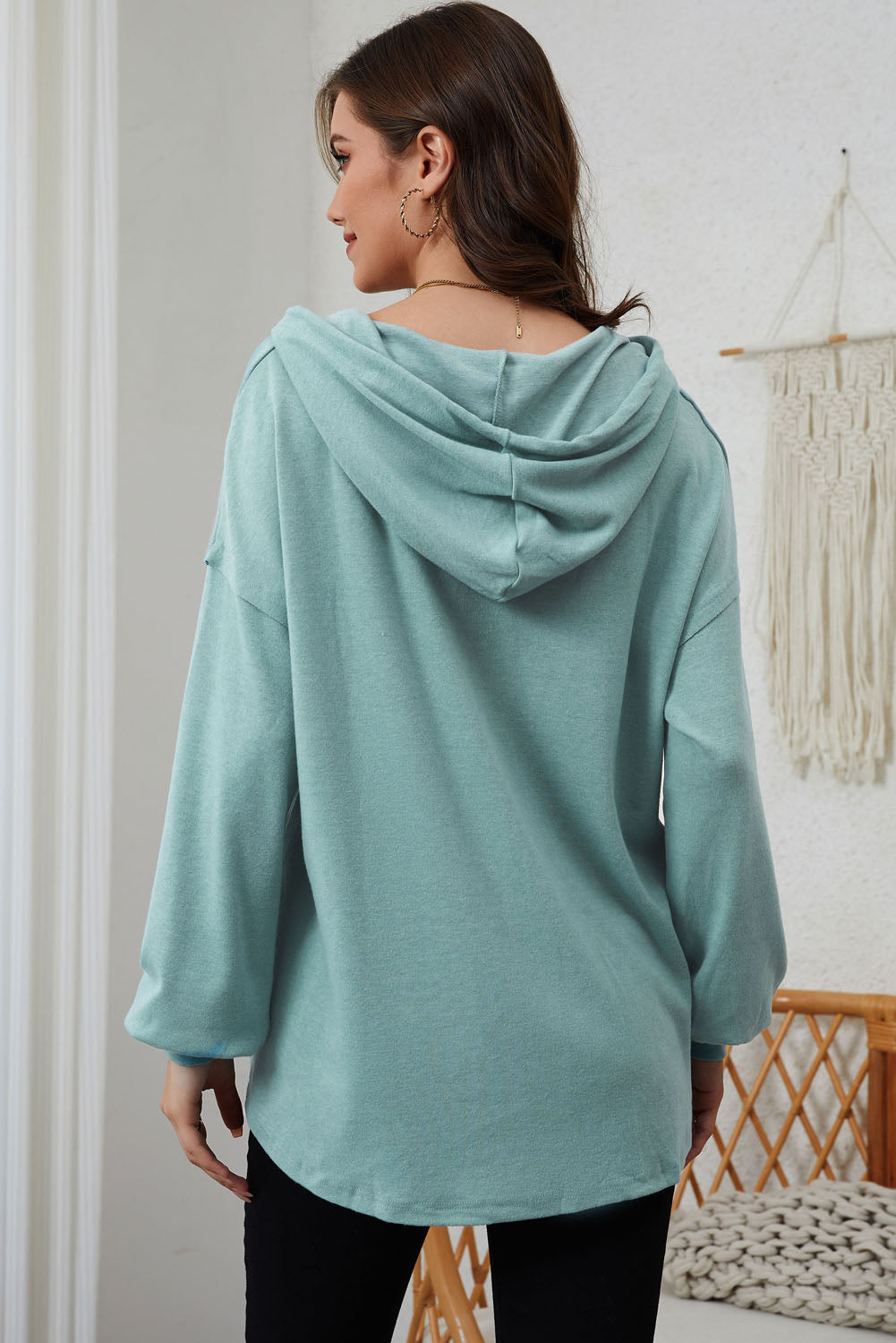 Sky Blue Buttoned High and Low Hem Hoodie with drawstring hood and tortoiseshell buttons, showcasing a relaxed fit and side slits.