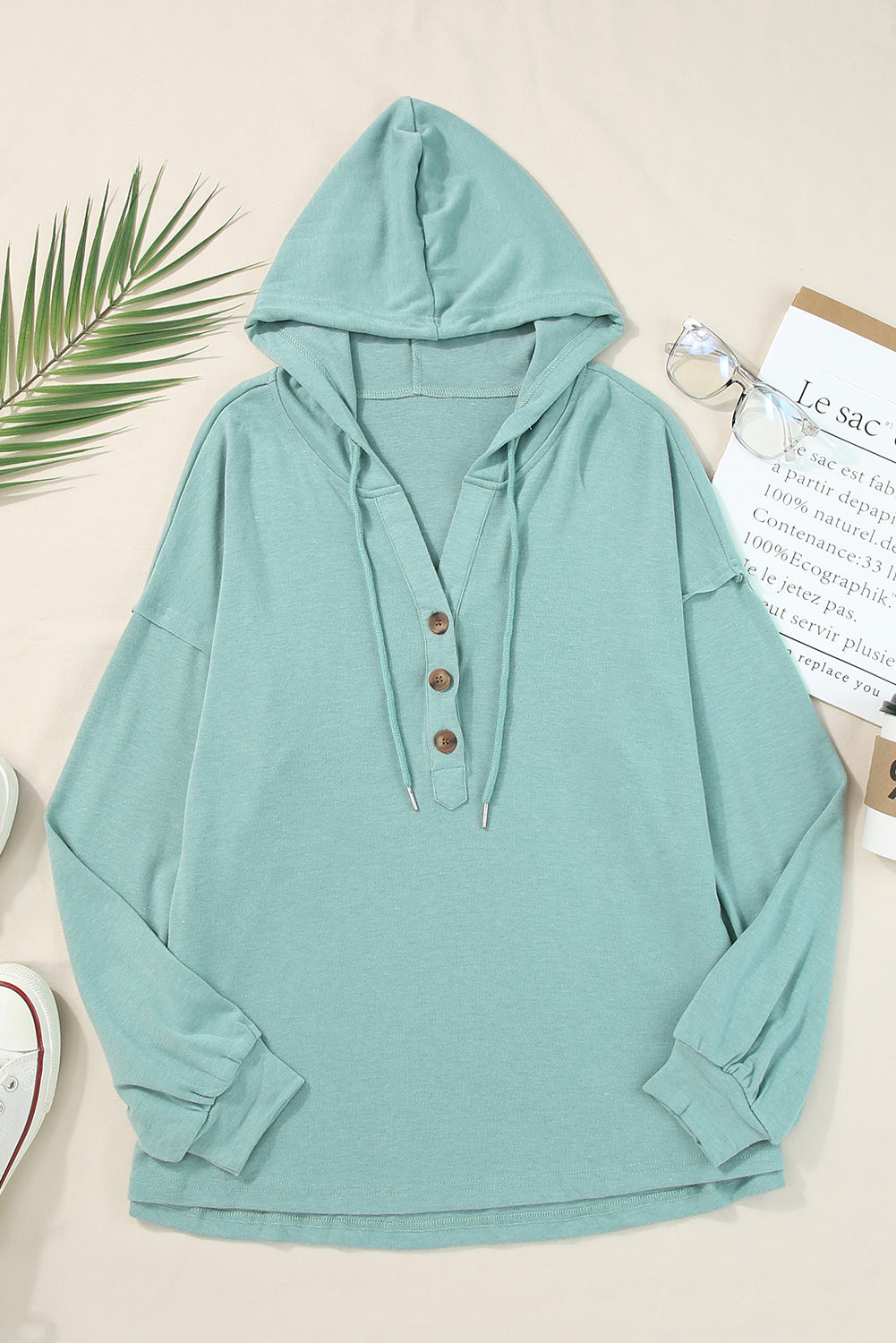 Sky Blue Buttoned High and Low Hem Hoodie with drawstring hood and tortoiseshell buttons, showcasing a relaxed fit and side slits.