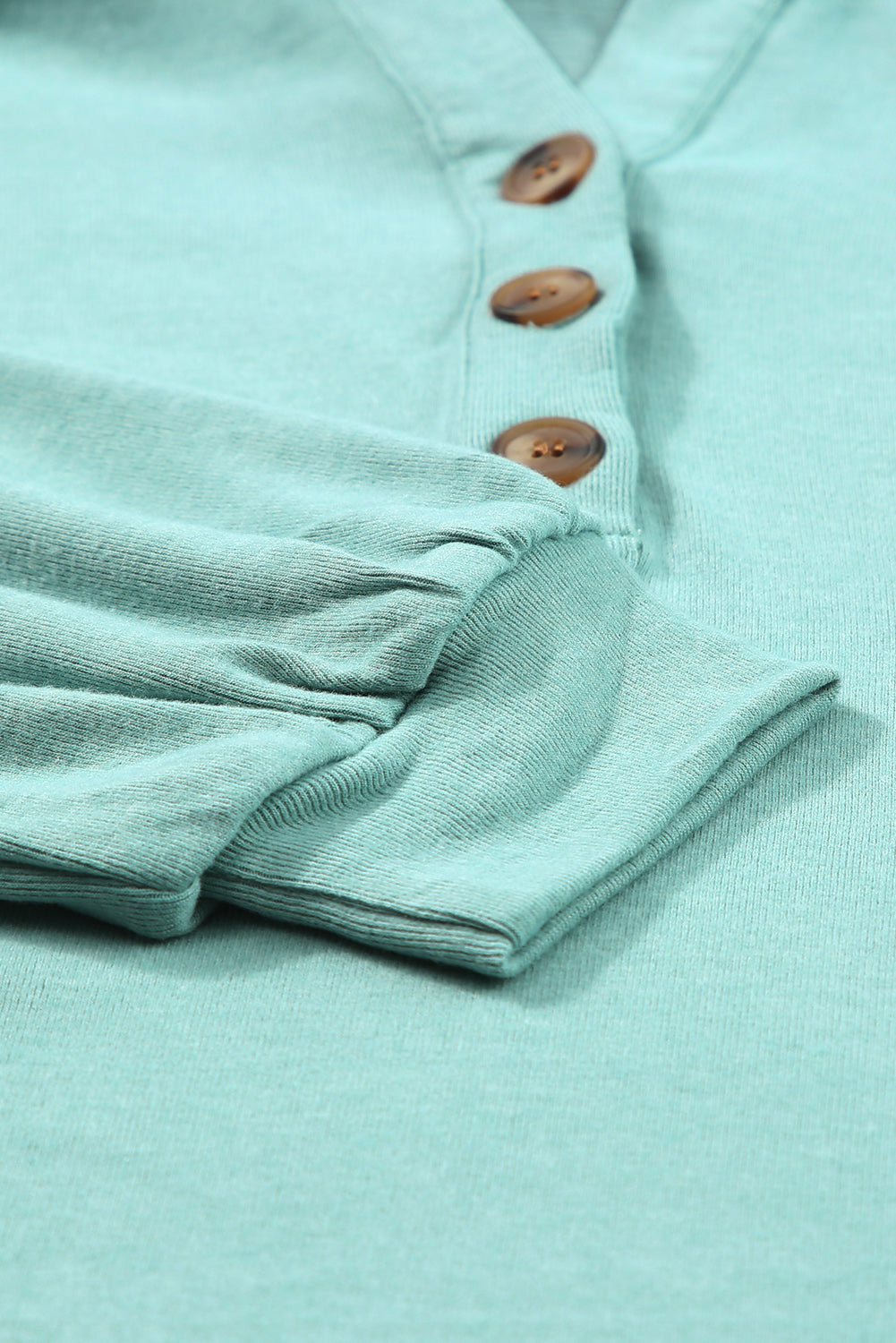 Sky Blue Buttoned High and Low Hem Hoodie with drawstring hood and tortoiseshell buttons, showcasing a relaxed fit and side slits.