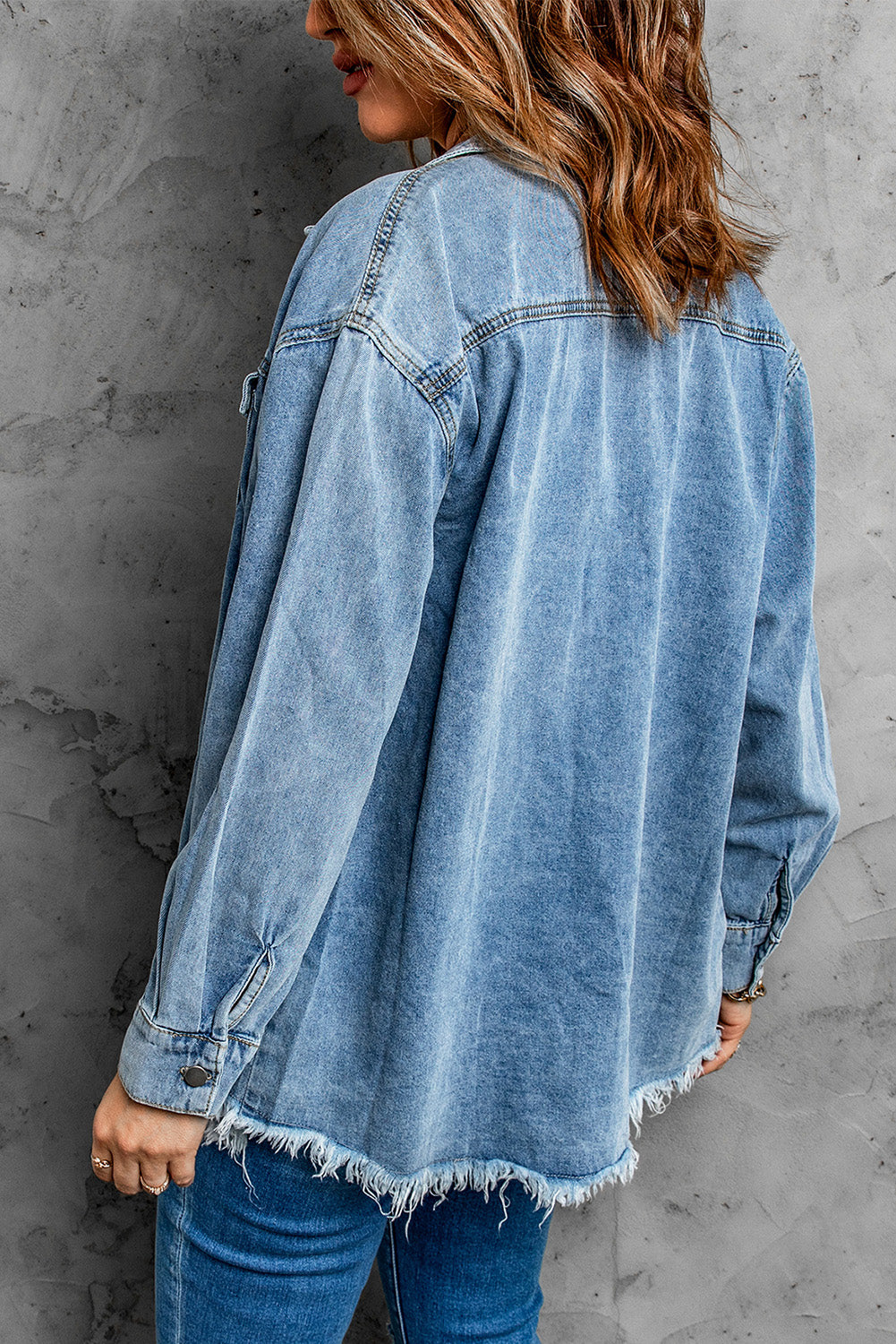 Sky blue denim jacket featuring a raw hem, button closure, and flap pocket, perfect for casual wear.