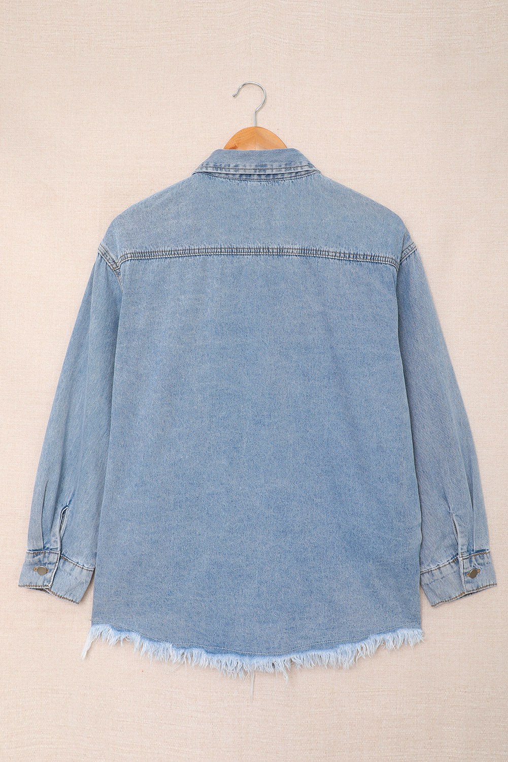 Sky blue denim jacket featuring a raw hem, button closure, and flap pocket, perfect for casual wear.