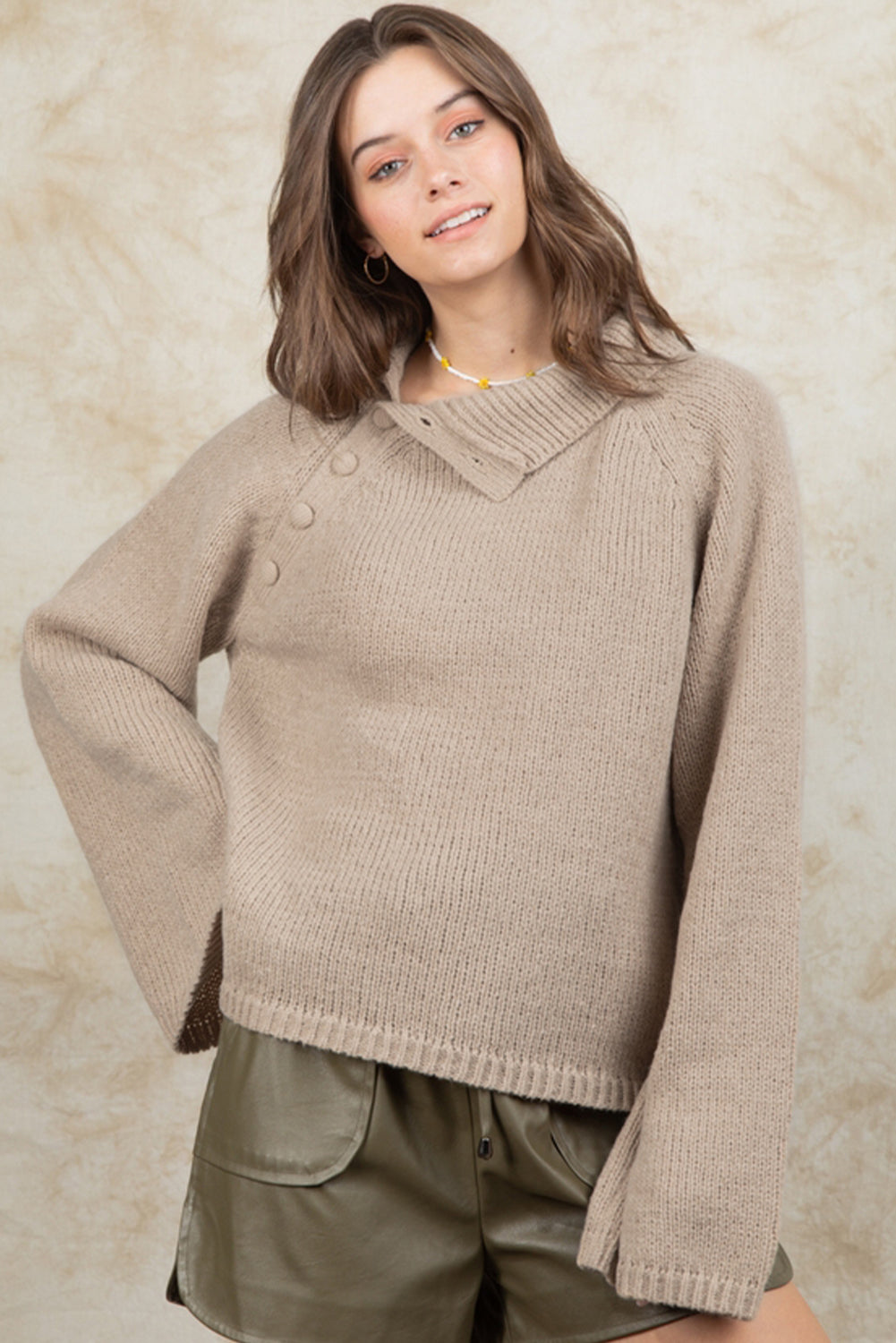 Smoke gray sweater with wide sleeves and high neck, featuring side buttons for adjustable styling.