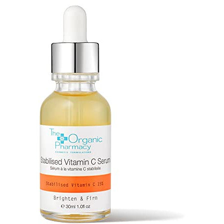 The Organic Pharmacy Stabilised Vitamin C Serum in a sleek glass bottle with a dropper, showcasing its vibrant orange color.