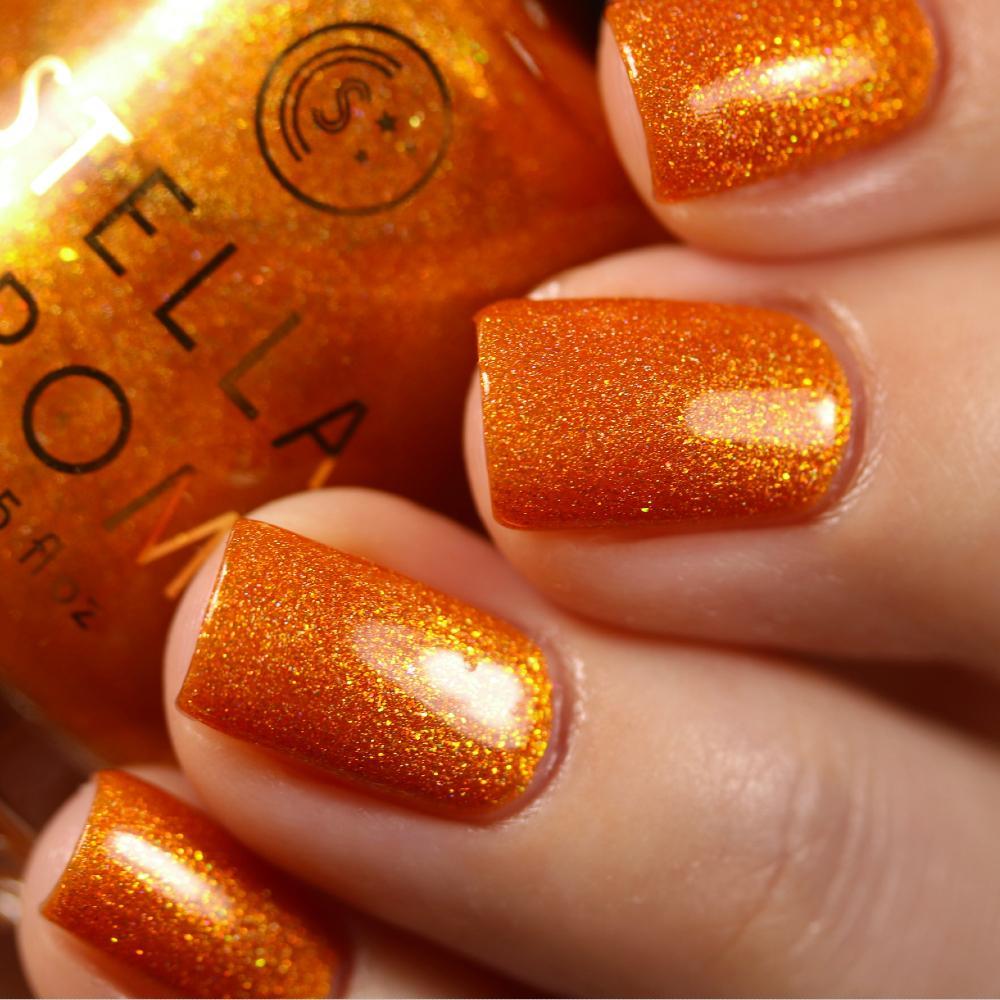 Stella Chroma Nail Polish in Hailey's Comet, a vivid orange holo with red and gold flash, displayed in a stylish bottle.