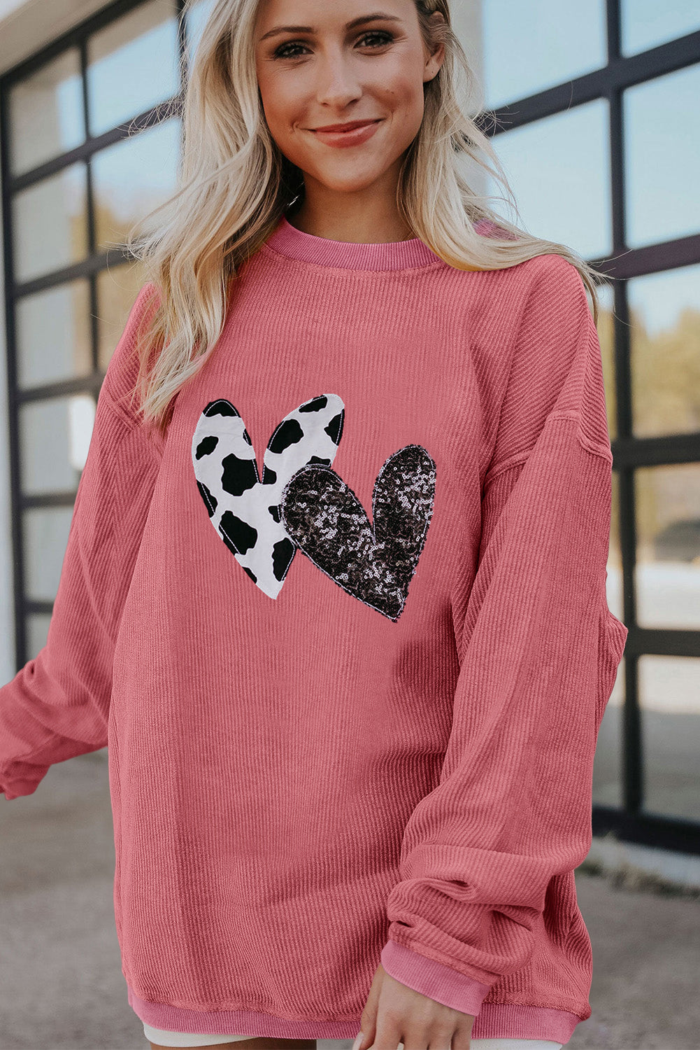 Strawberry pink corded sweatshirt featuring leopard print and sequin heart graphics, perfect for Valentine's Day fashion.