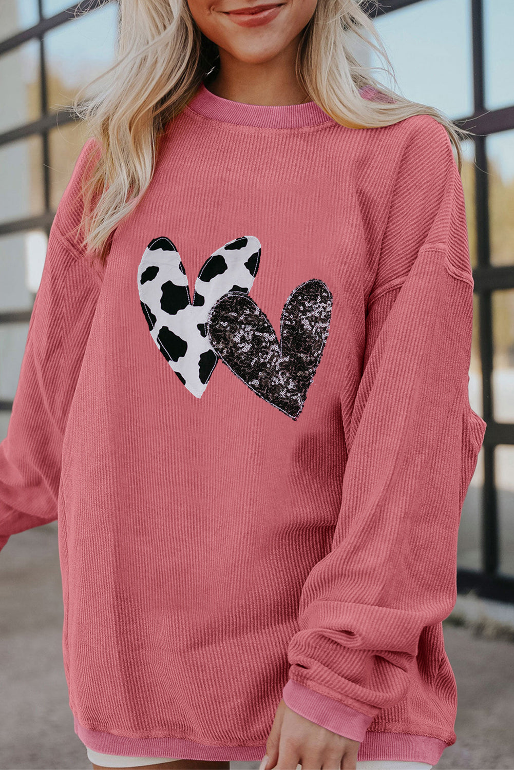 Strawberry pink corded sweatshirt featuring leopard print and sequin heart graphics, perfect for Valentine's Day fashion.