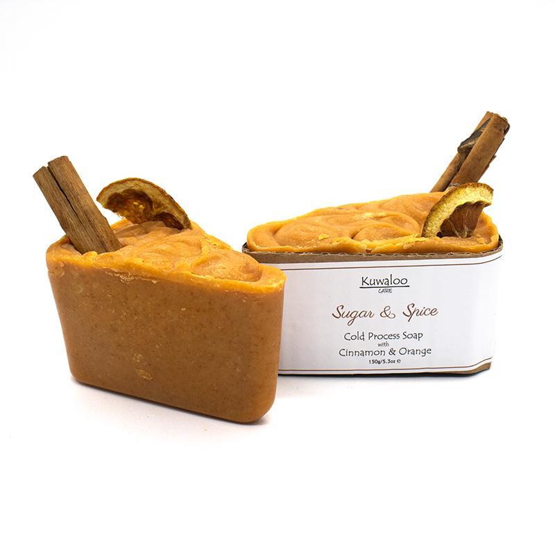 A beautifully crafted 'Sugar and Spice' soap featuring dried orange and a cinnamon stick, showcasing its vibrant orange color.