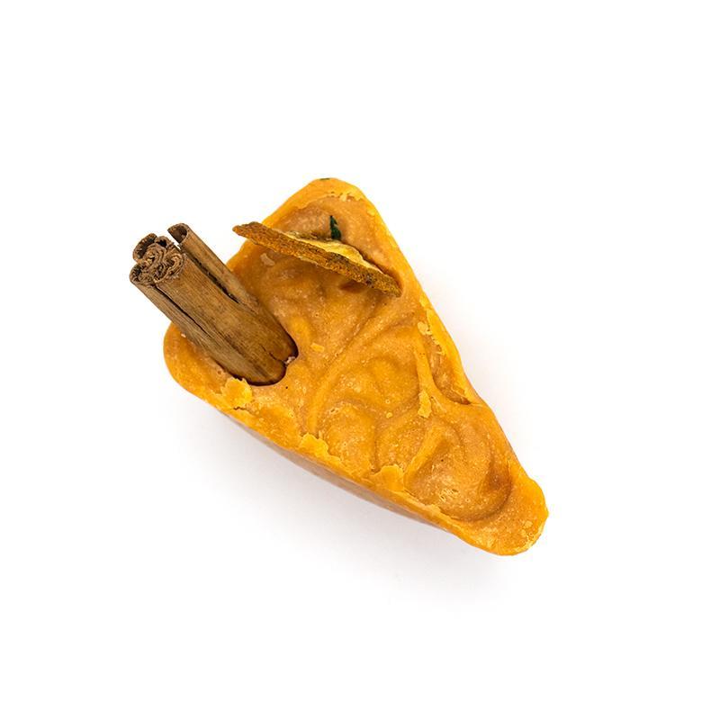 A beautifully crafted 'Sugar and Spice' soap featuring dried orange and a cinnamon stick, showcasing its vibrant orange color.