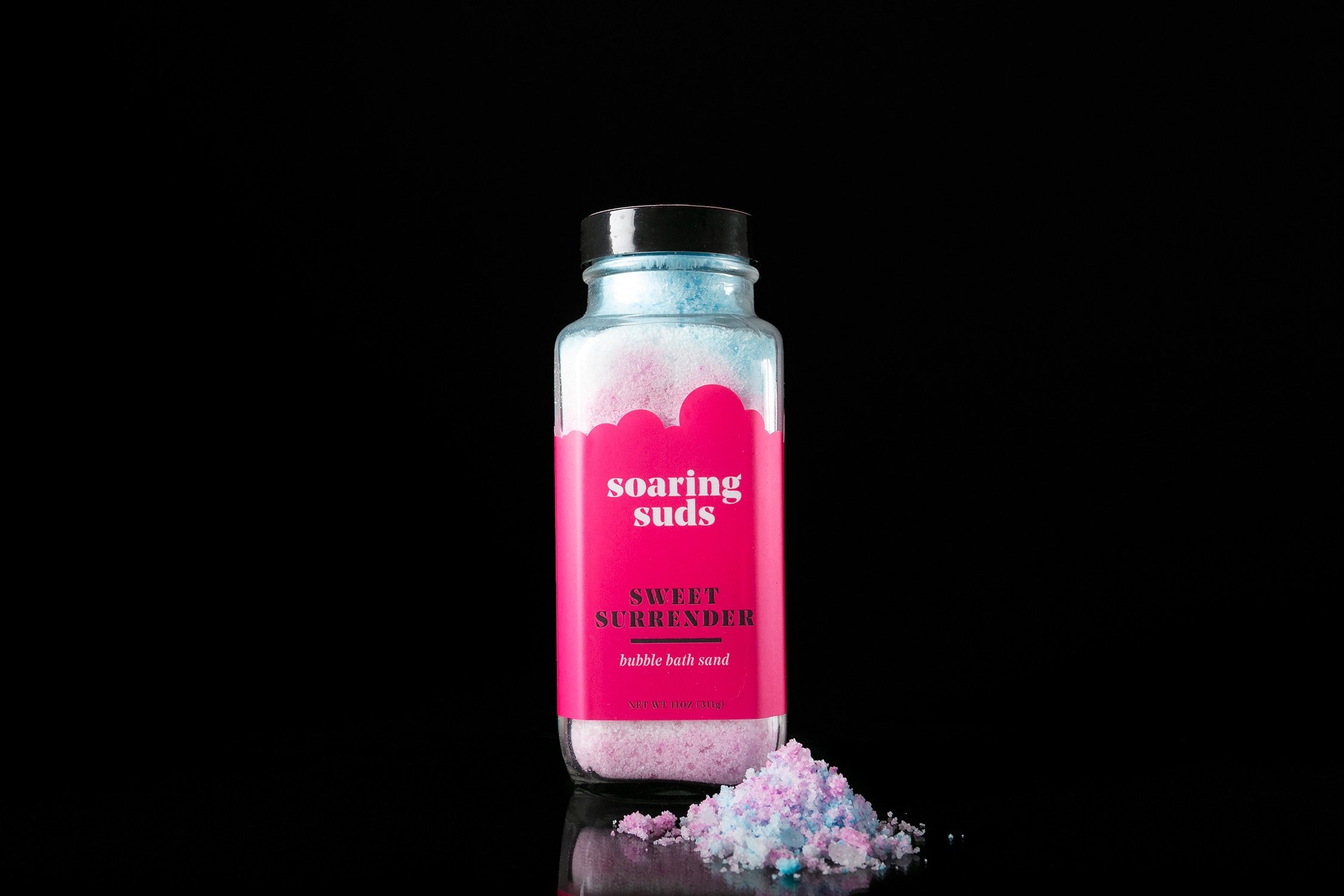 Sweet Surrender Bath Sand in a decorative jar, showcasing its vibrant colors and texture, perfect for a luxurious bath experience.