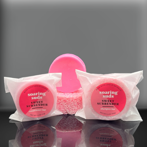 Sweet Surrender Shampoo & Conditioner bars with strawberry and champagne scent, showcasing their eco-friendly packaging and luxurious texture.