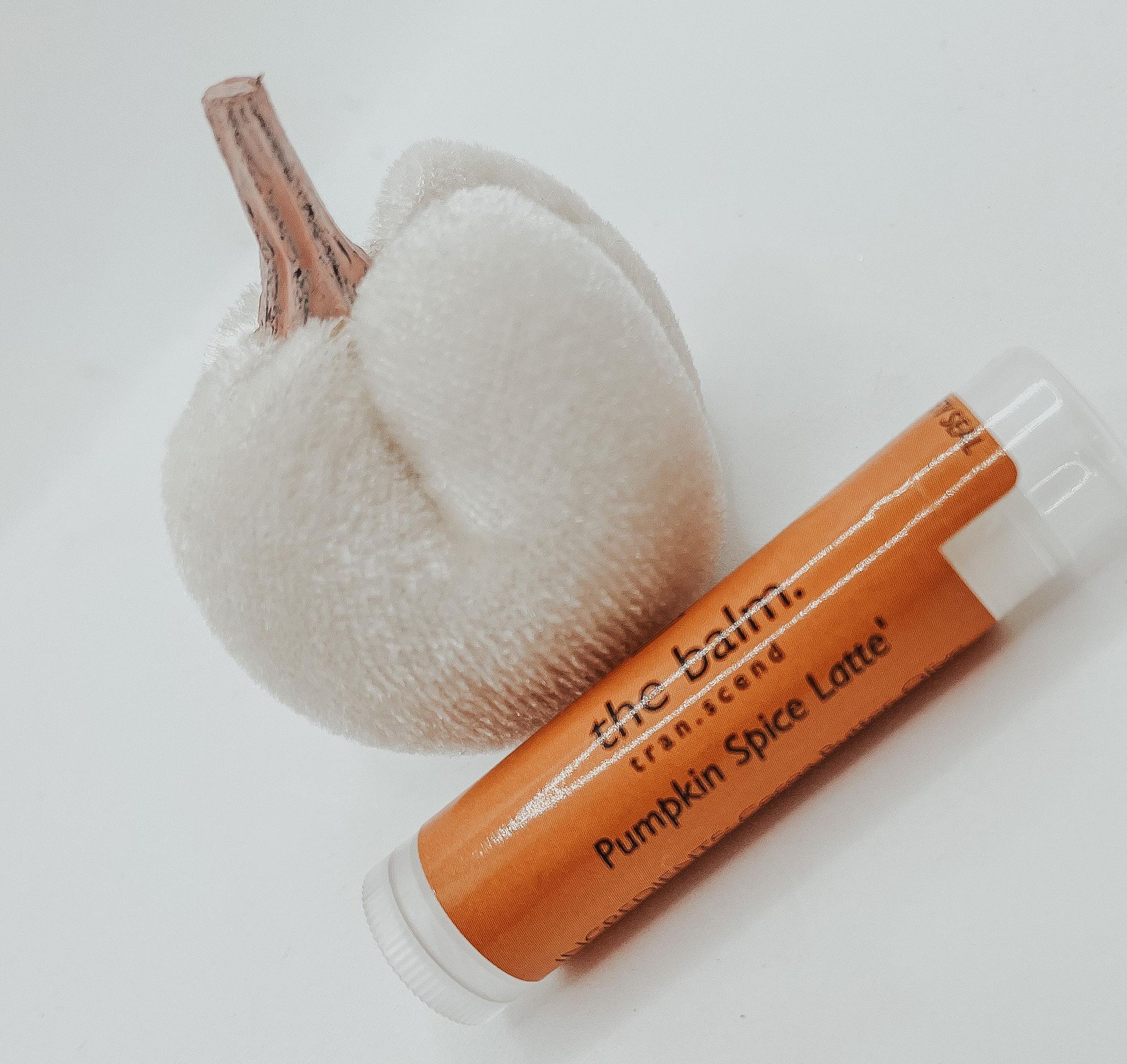 The Balm - Pumpkin Spice Latte lip balm in a stylish tube, showcasing its warm autumn-inspired design and inviting pumpkin spice scent.