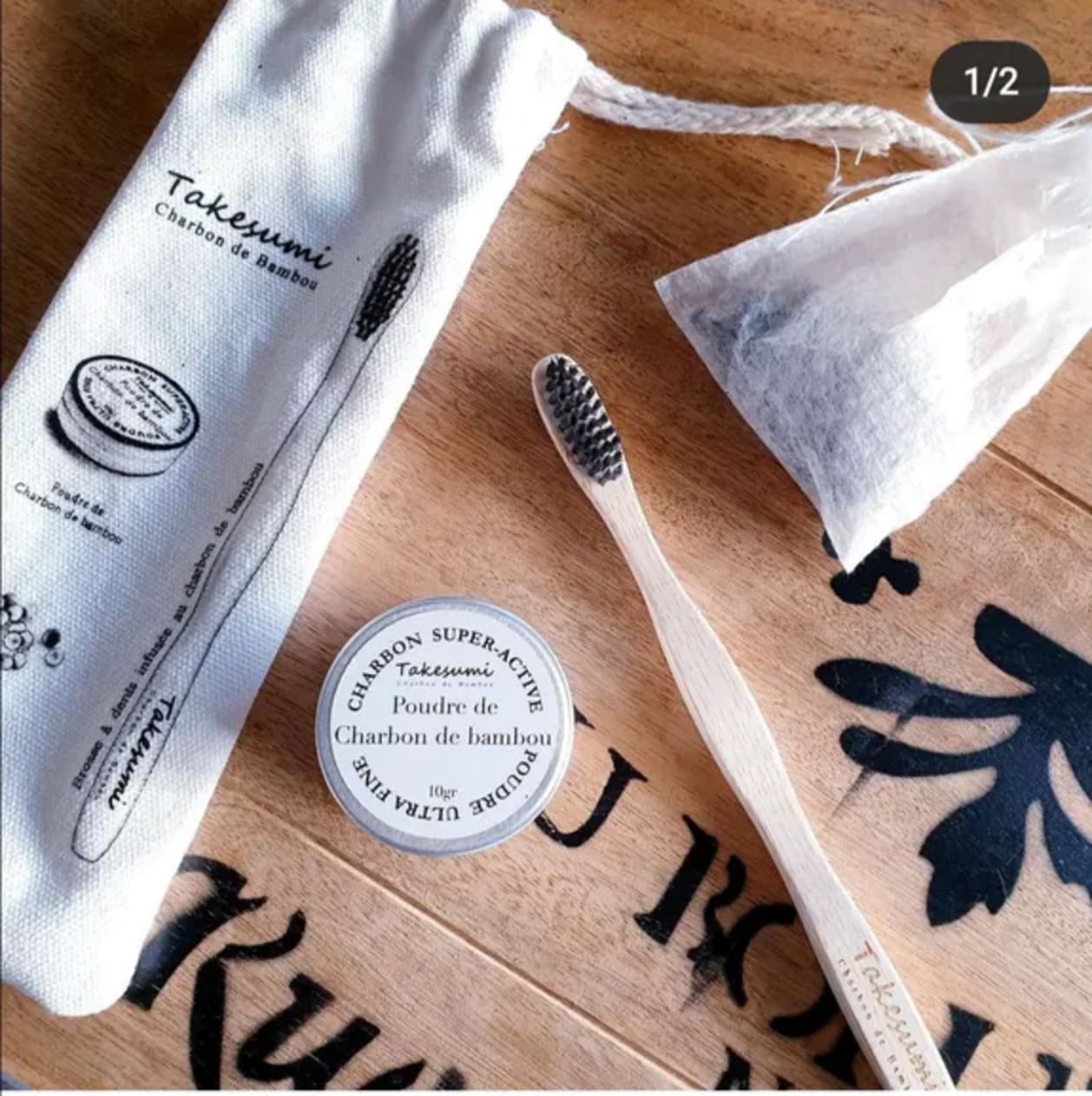 Trio hygiène bucco-dentaire au charbon de bambou comprenant une brosse à dents, de la poudre de charbon et des billes céramiques, présenté dans un pochon en coton naturel.