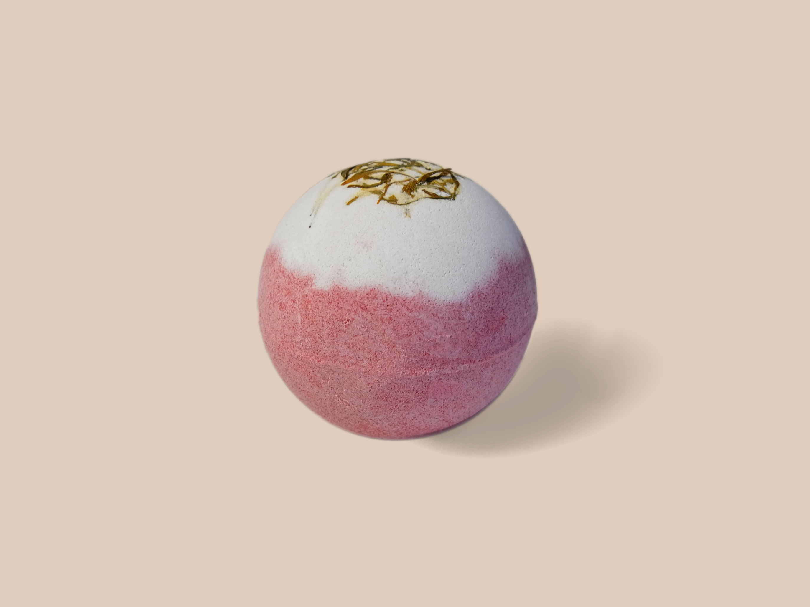 A Vanilla Coconut Bath Bomb surrounded by flower petals, showcasing its organic ingredients and vibrant colors.