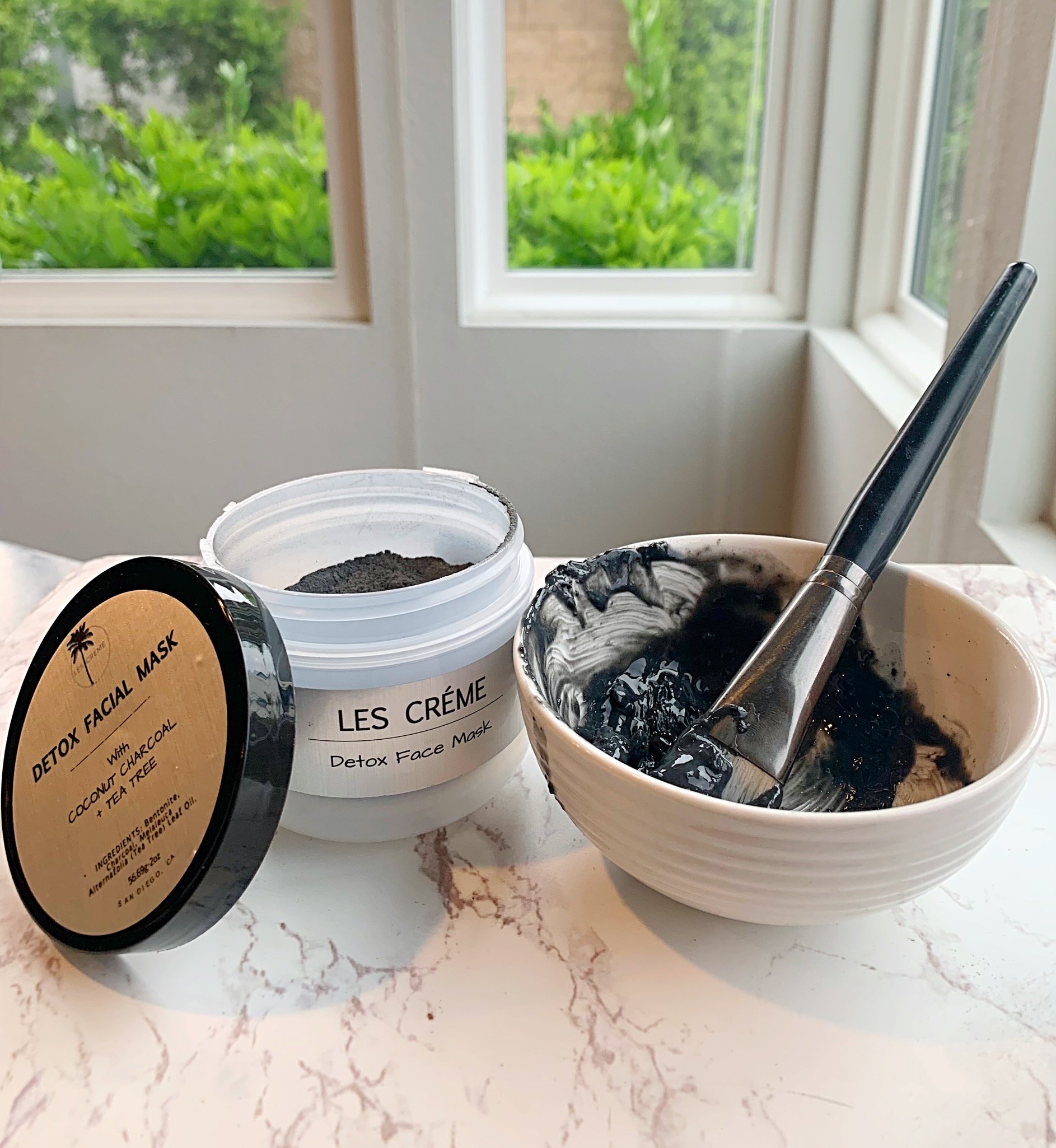 A jar of Weekly Detox Facial Mask with activated coconut charcoal and bentonite clay, showcasing its creamy texture and natural ingredients.