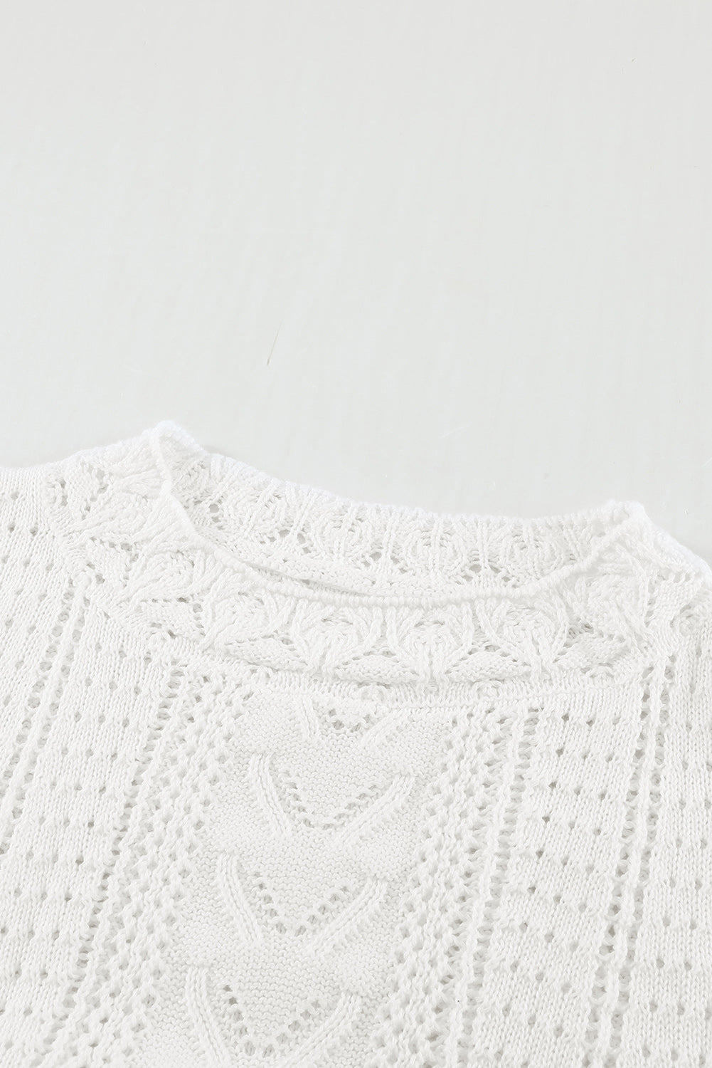 A stylish white crochet lace pointelle knit sweater featuring a scalloped neckline and sheer lace sleeves, perfect for casual and chic outfits.