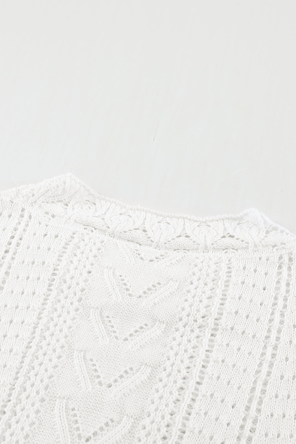 A stylish white crochet lace pointelle knit sweater featuring a scalloped neckline and sheer lace sleeves, perfect for casual and chic outfits.