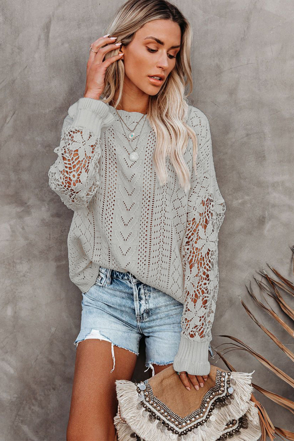 A stylish white crochet lace pointelle knit sweater featuring a scalloped neckline and sheer lace sleeves, perfect for casual and chic outfits.