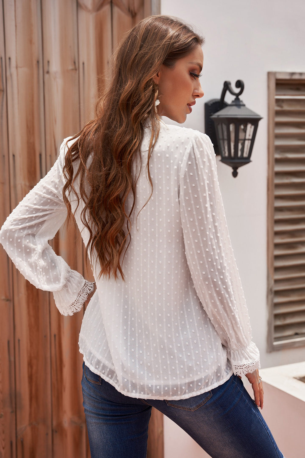 A stylish white blouse featuring a v-neck design, swiss dot pattern, and lace trim on the neckline and sleeves, perfect for casual or formal wear.