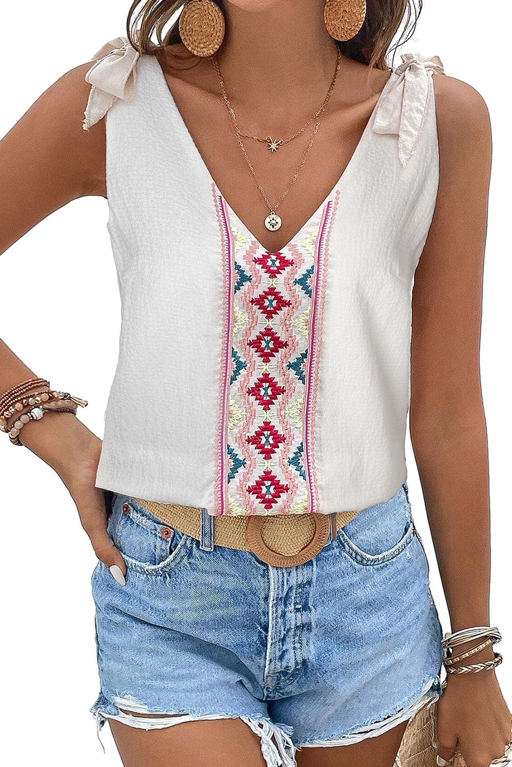 White tank top with floral embroidery and knot straps, showcasing a textured fabric design.