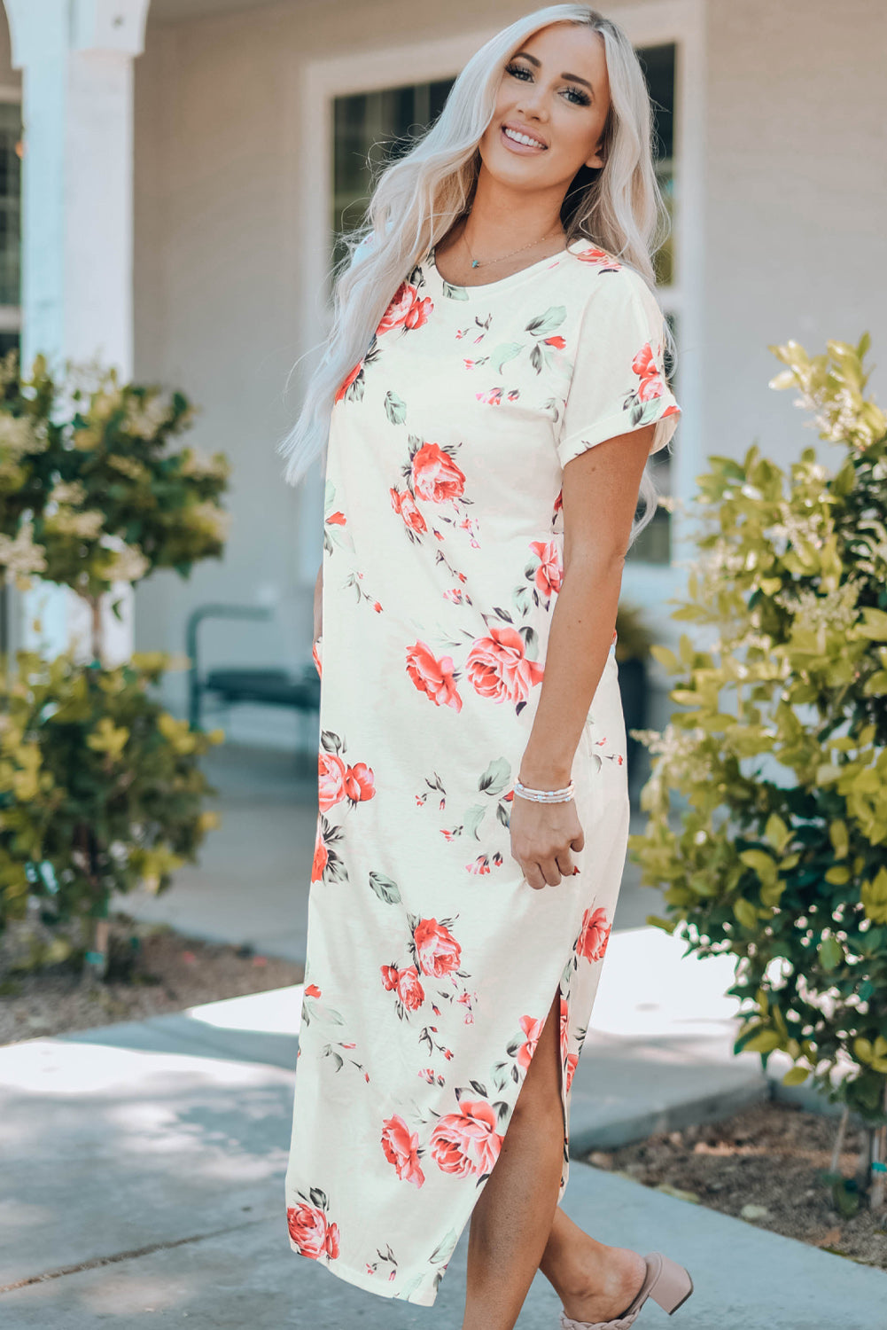 A stylish white t shirt dress featuring a vibrant floral print, side slits, and short sleeves, perfect for summer outings.