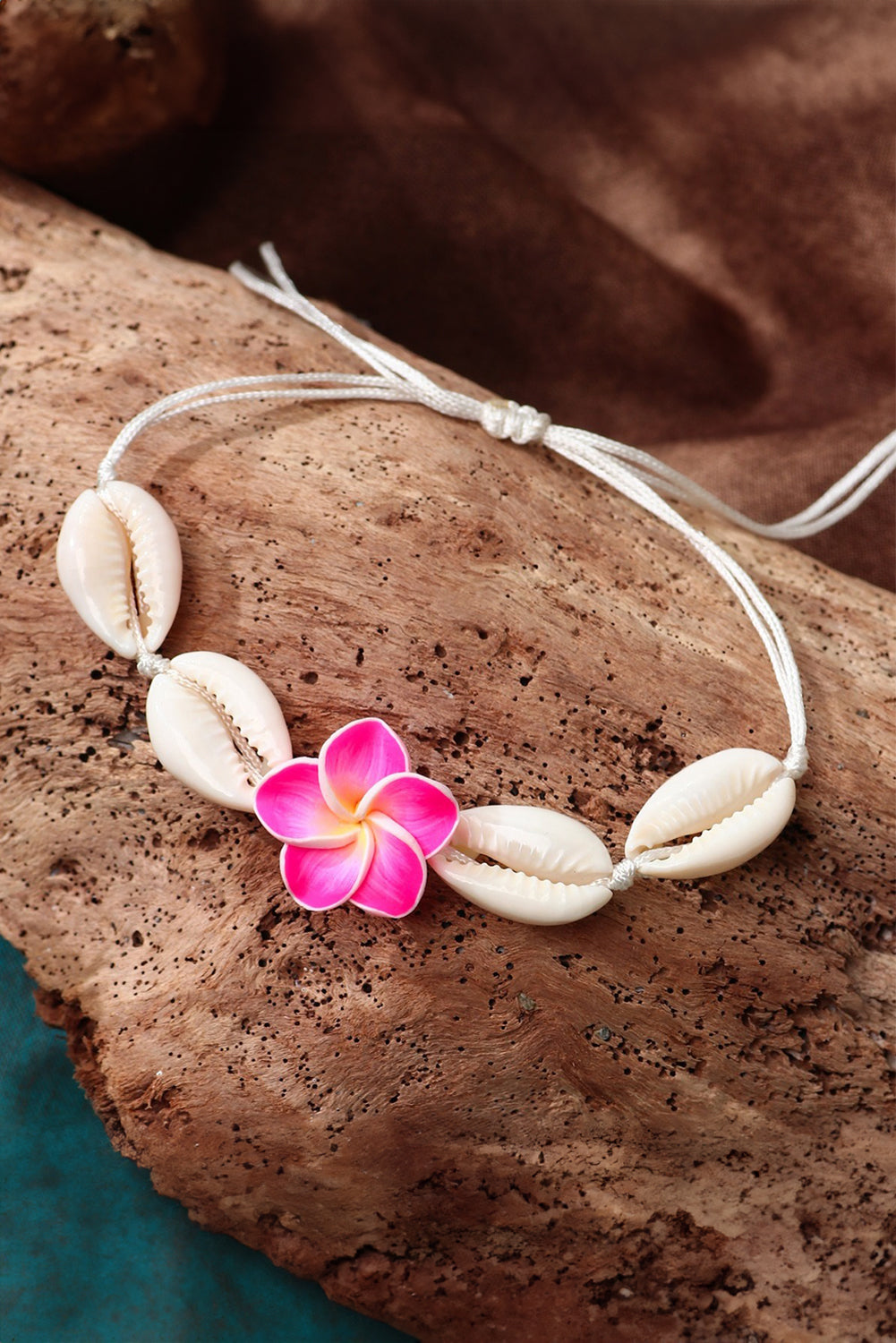 A stylish adjustable bracelet featuring a white flower design and seashell accents, perfect for any occasion.