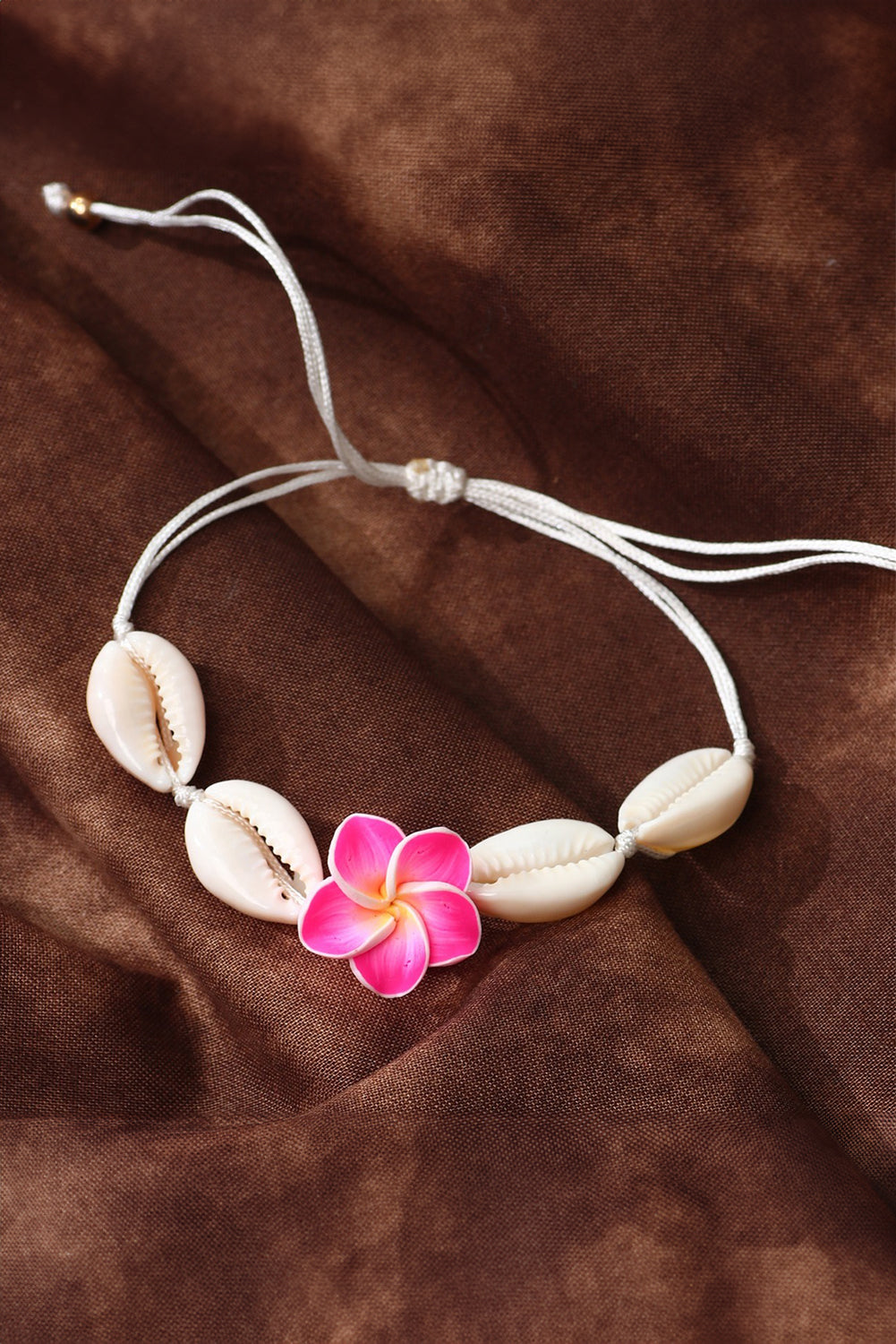 A stylish adjustable bracelet featuring a white flower design and seashell accents, perfect for any occasion.