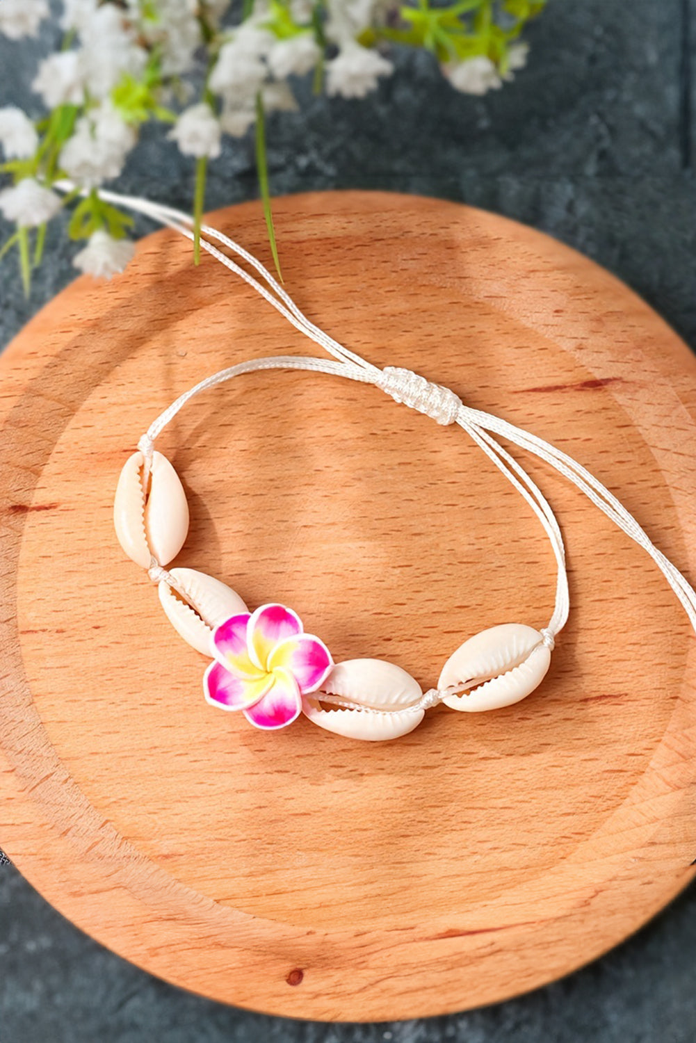 A stylish adjustable bracelet featuring a white flower design and seashell accents, perfect for any occasion.