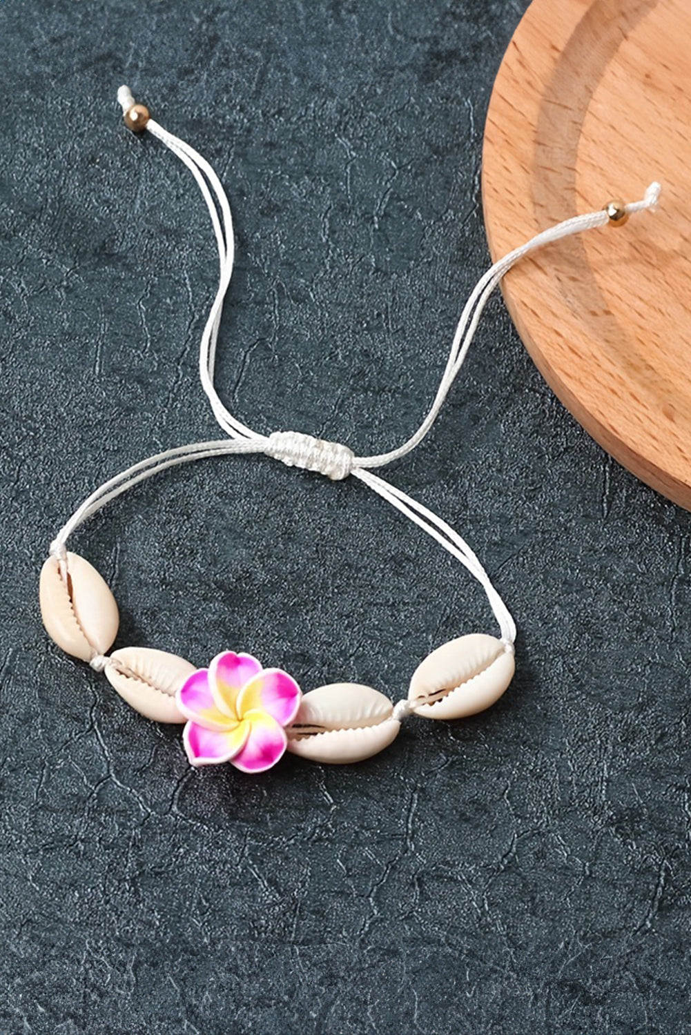 A stylish adjustable bracelet featuring a white flower design and seashell accents, perfect for any occasion.