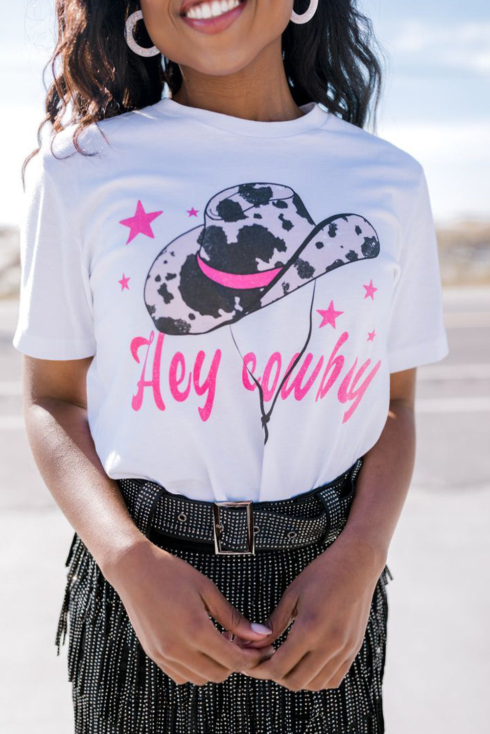 White t-shirt featuring a humorous 'Hey Cowboy' print with a bold cowboy hat design, perfect for casual wear.