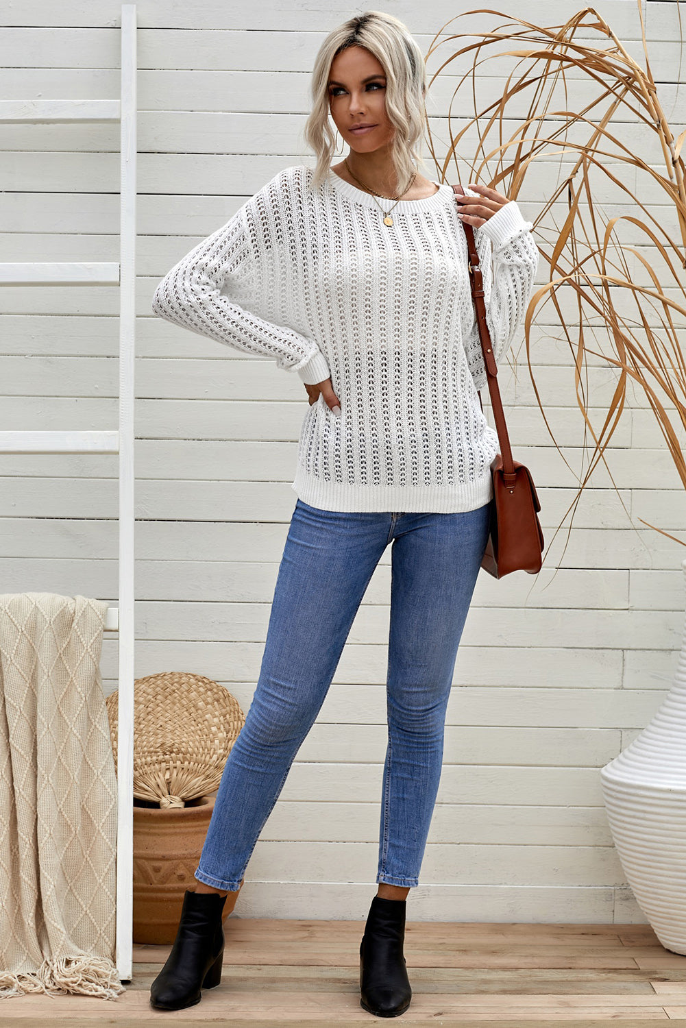 A stylish white knitted sweater featuring a hollow-out design and drop shoulder style, perfect for a chic and relaxed look.