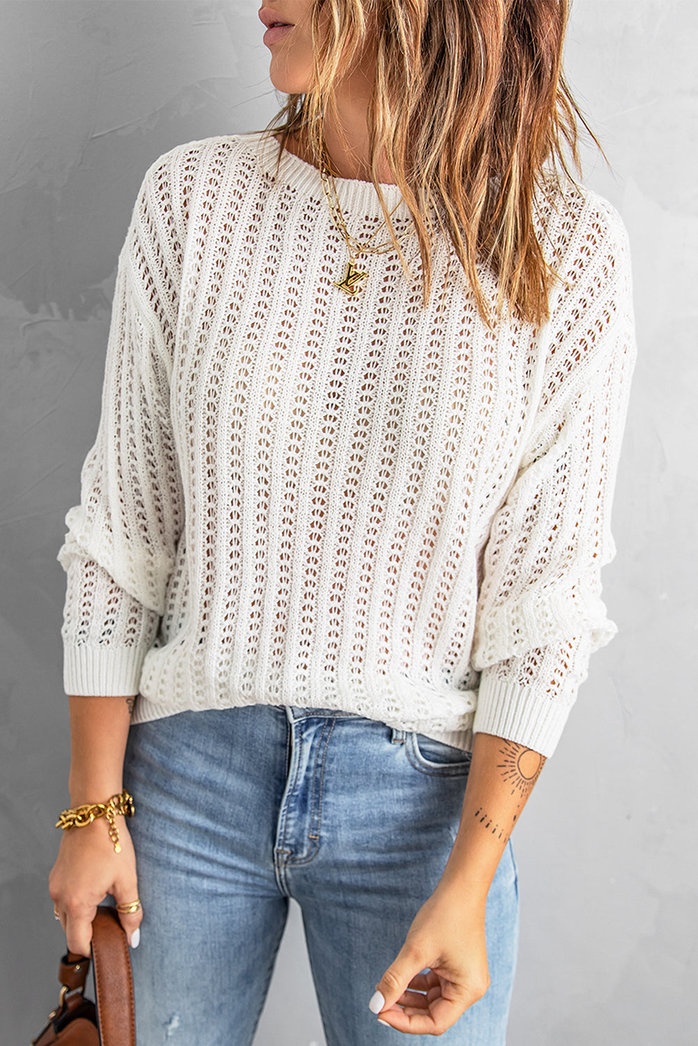 A stylish white knitted sweater featuring a hollow-out design and drop shoulder style, perfect for a chic and relaxed look.