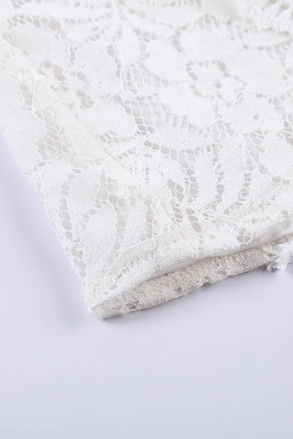 A stylish white lace v neck tank top featuring a delicate floral lace design, sleeveless cut, and a daring hollow-out back.