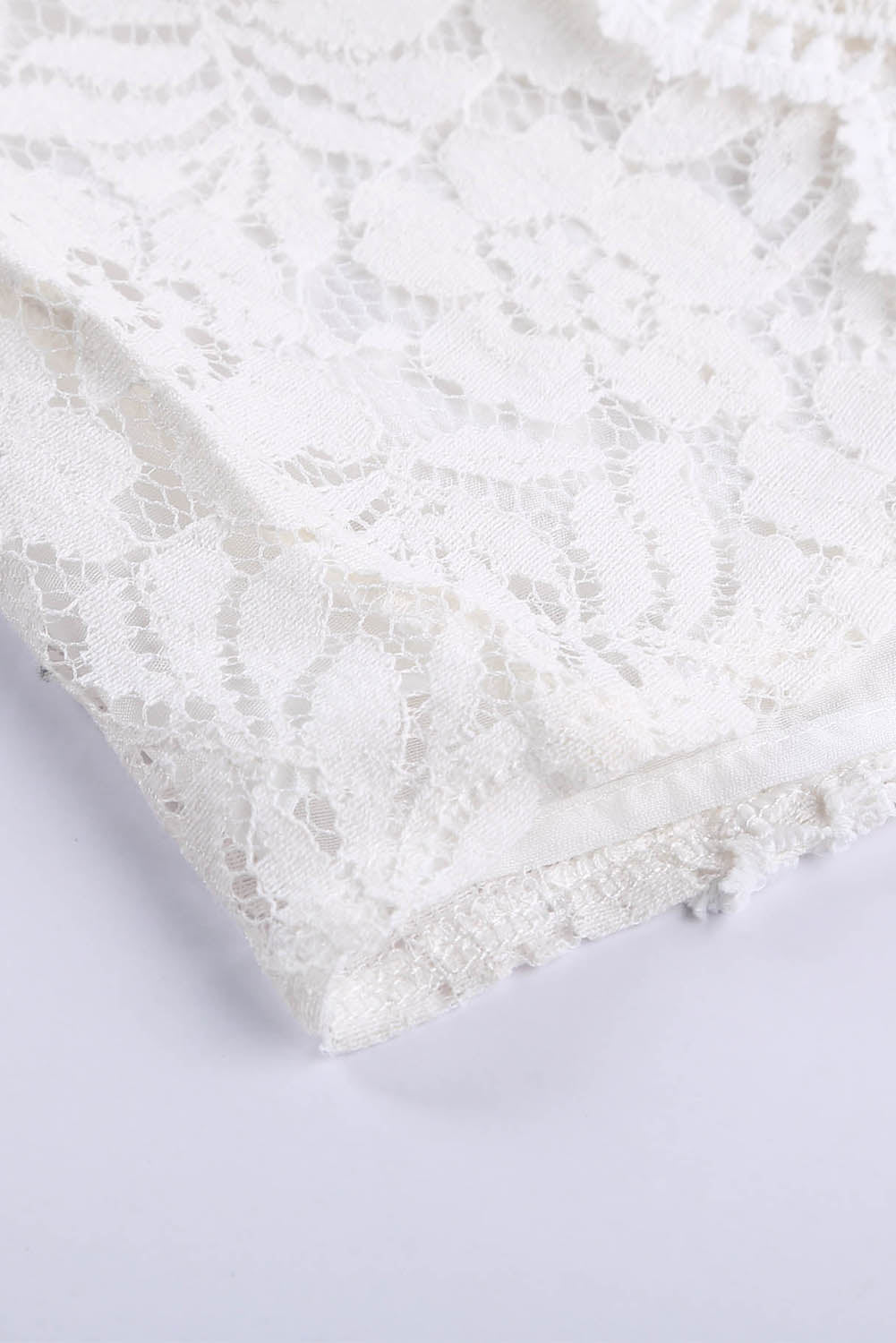 A stylish white lace v neck tank top featuring a delicate floral lace design, sleeveless cut, and a daring hollow-out back.