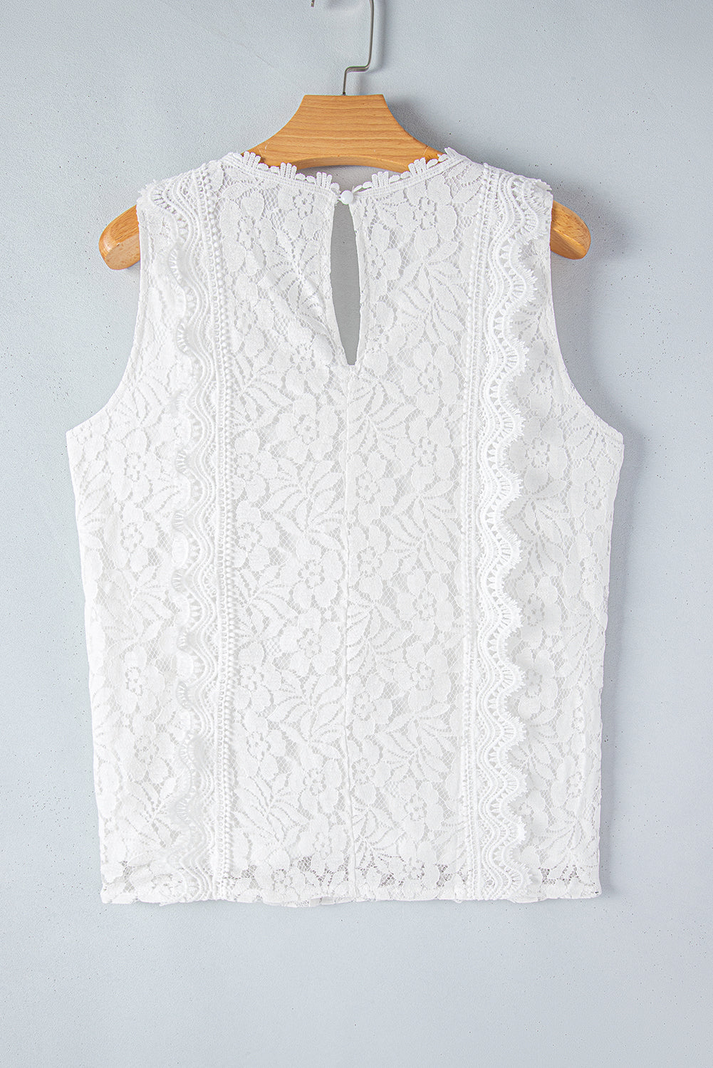 A stylish white lace v neck tank top featuring a delicate floral lace design, sleeveless cut, and a daring hollow-out back.