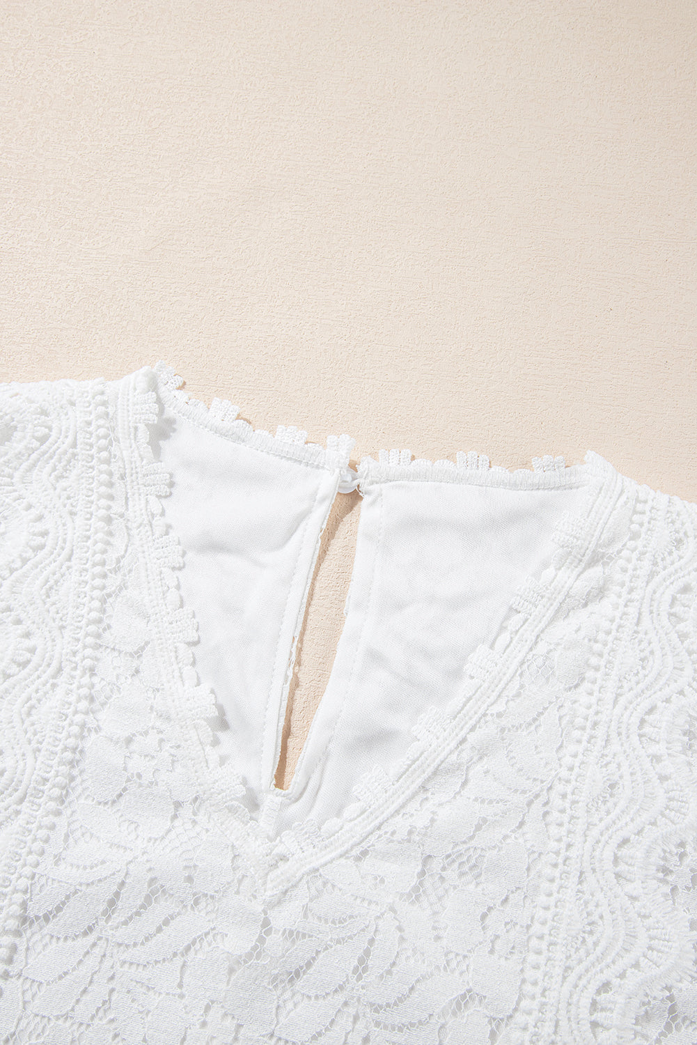 A stylish white lace v neck tank top featuring a delicate floral lace design, sleeveless cut, and a daring hollow-out back.