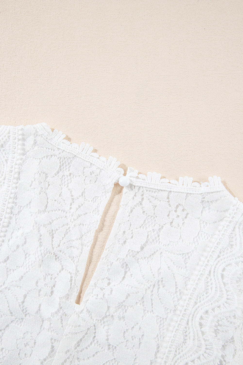 A stylish white lace v neck tank top featuring a delicate floral lace design, sleeveless cut, and a daring hollow-out back.