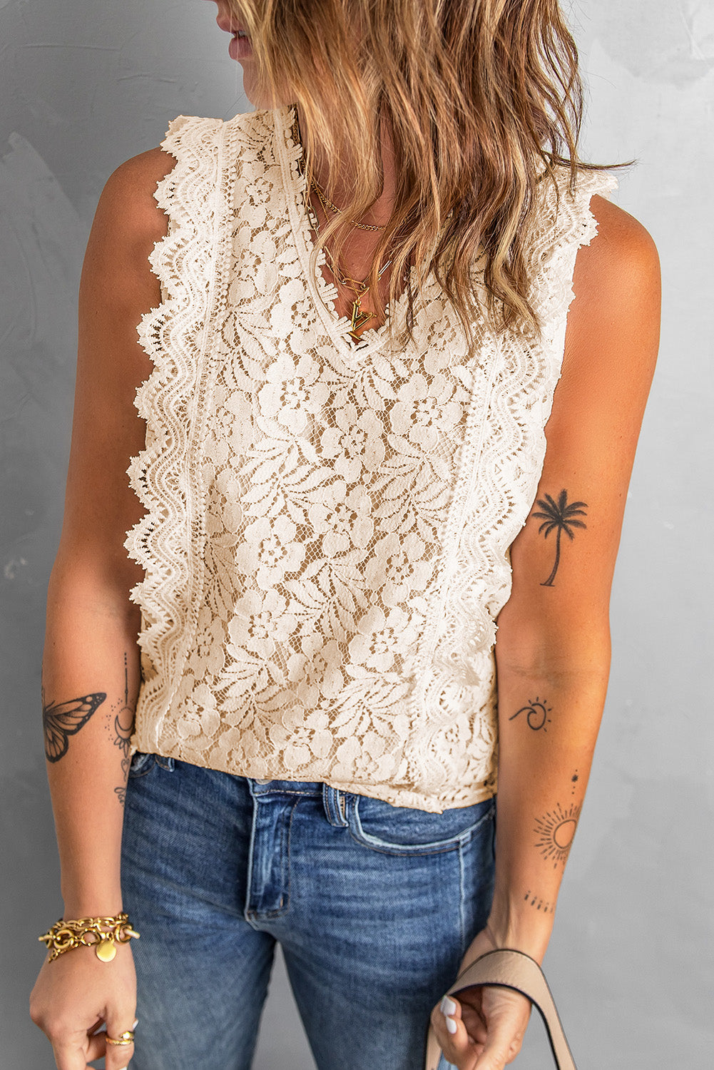 A stylish white lace v neck tank top featuring a delicate floral lace design, sleeveless cut, and a daring hollow-out back.