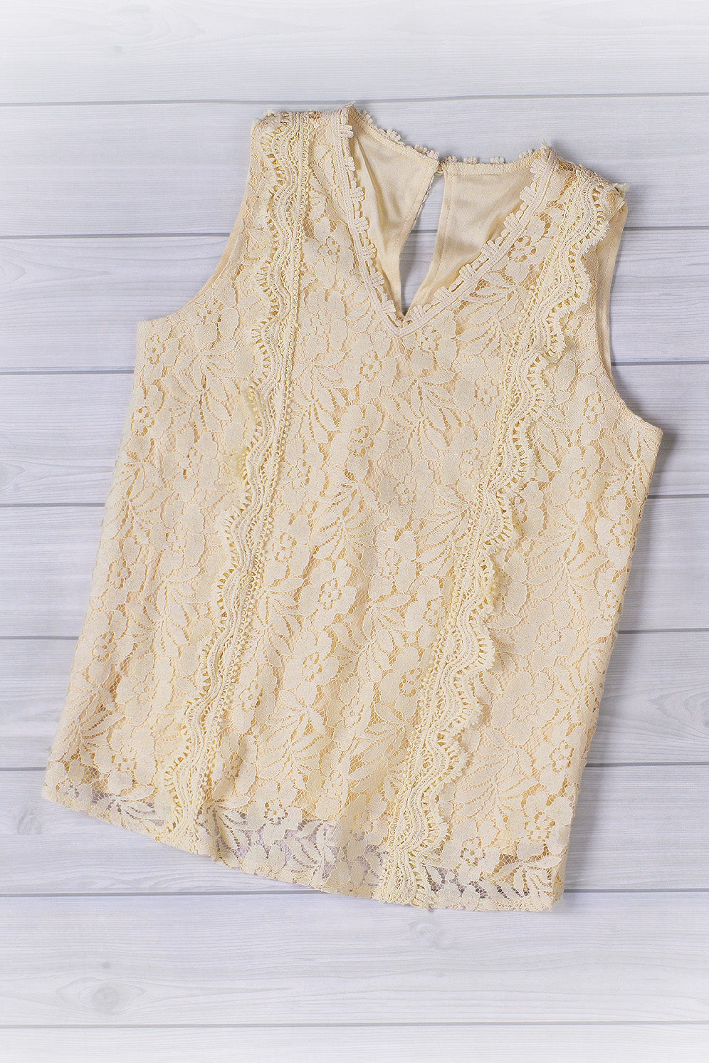 A stylish white lace v neck tank top featuring a delicate floral lace design, sleeveless cut, and a daring hollow-out back.