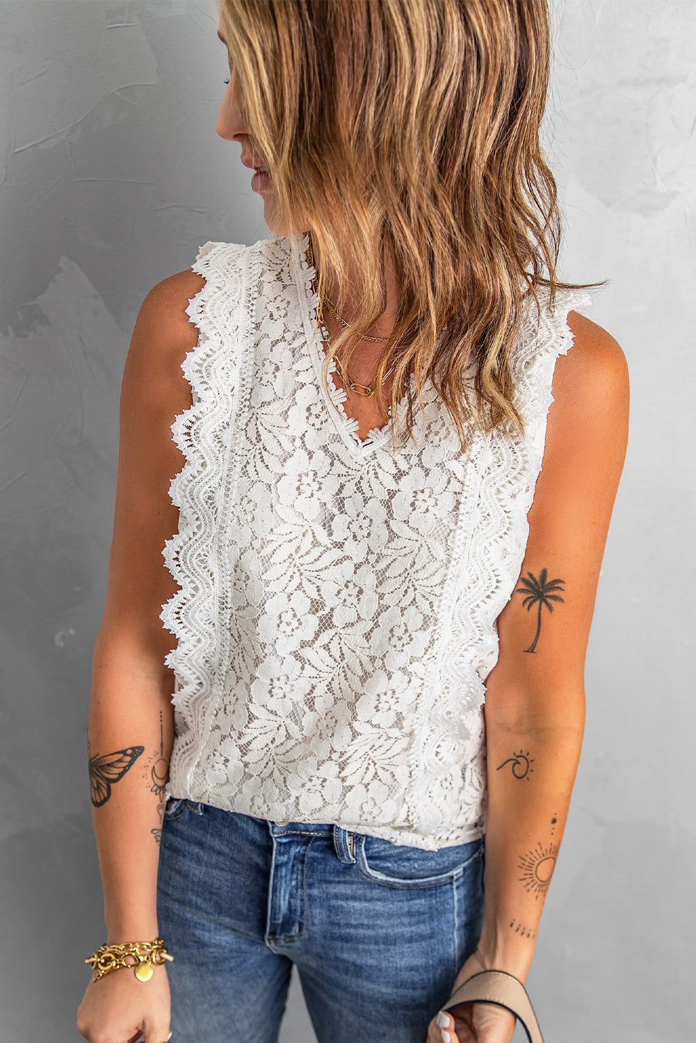 A stylish white lace v neck tank top featuring a delicate floral lace design, sleeveless cut, and a daring hollow-out back.